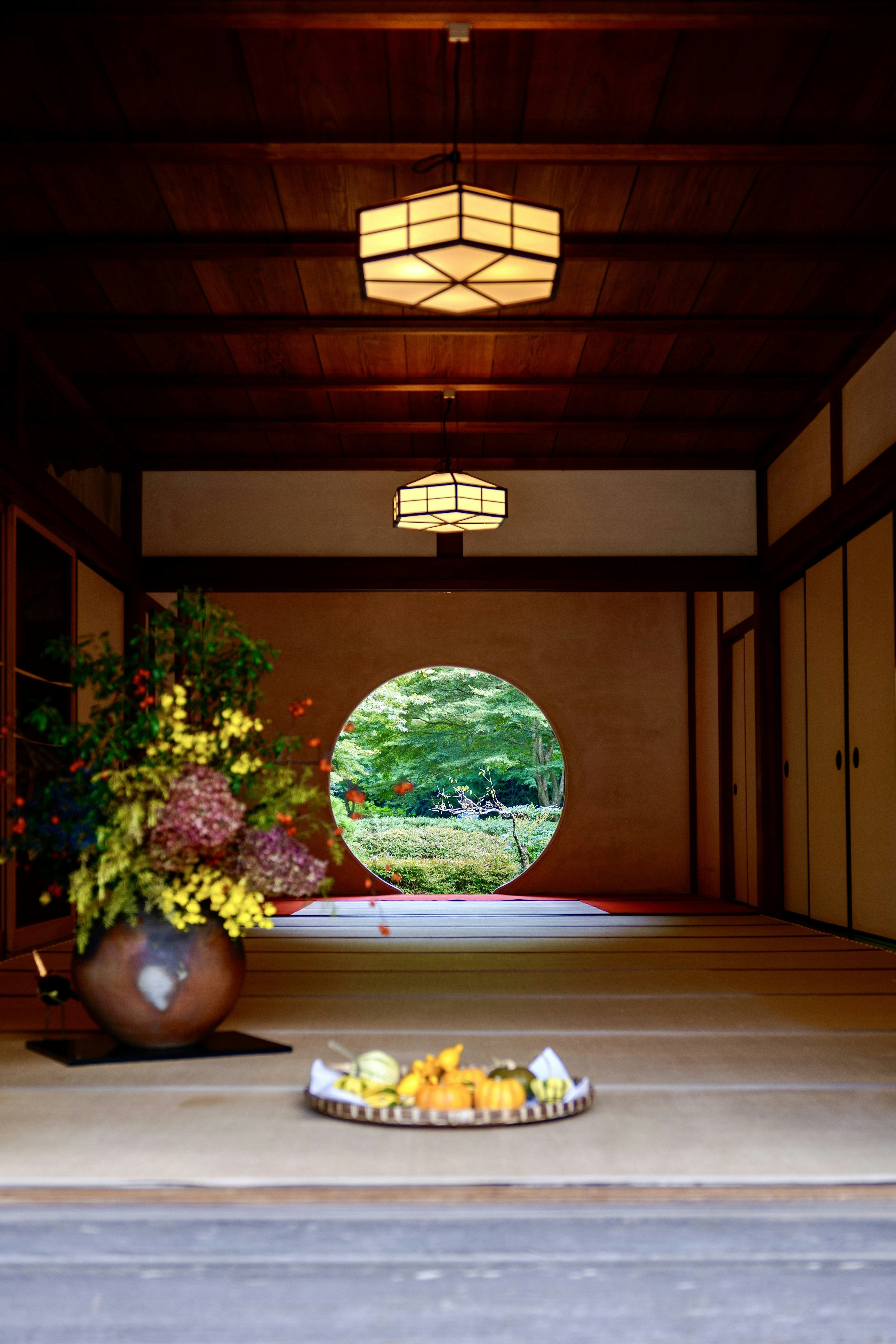 View of a serene garden through a circular doorway with floral arrangements