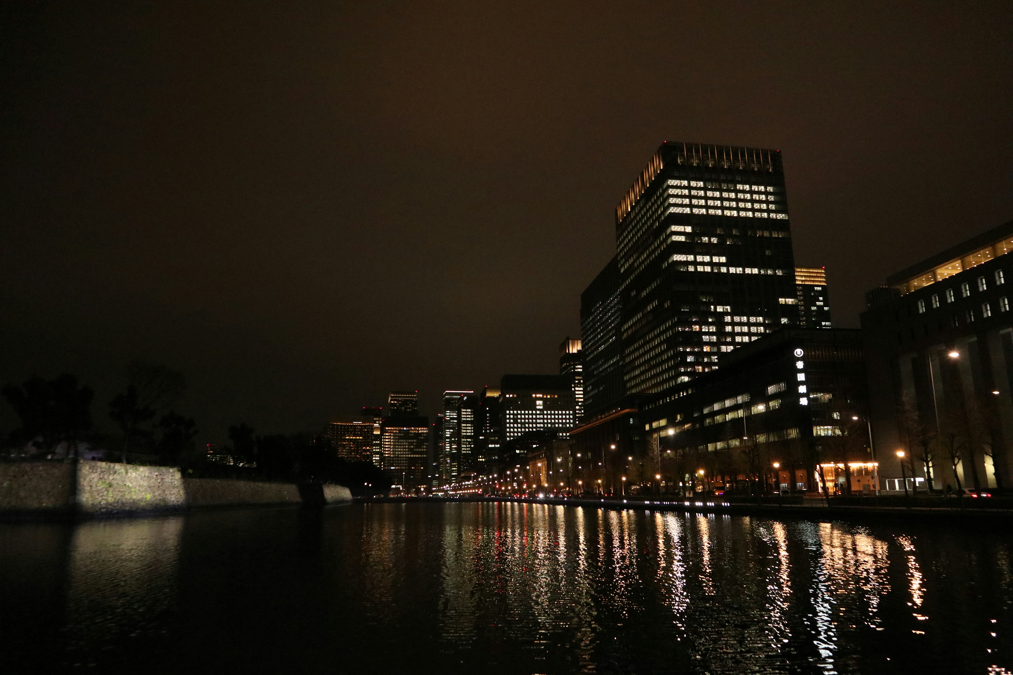 Edifici moderni lungo il fiume di notte con riflessi