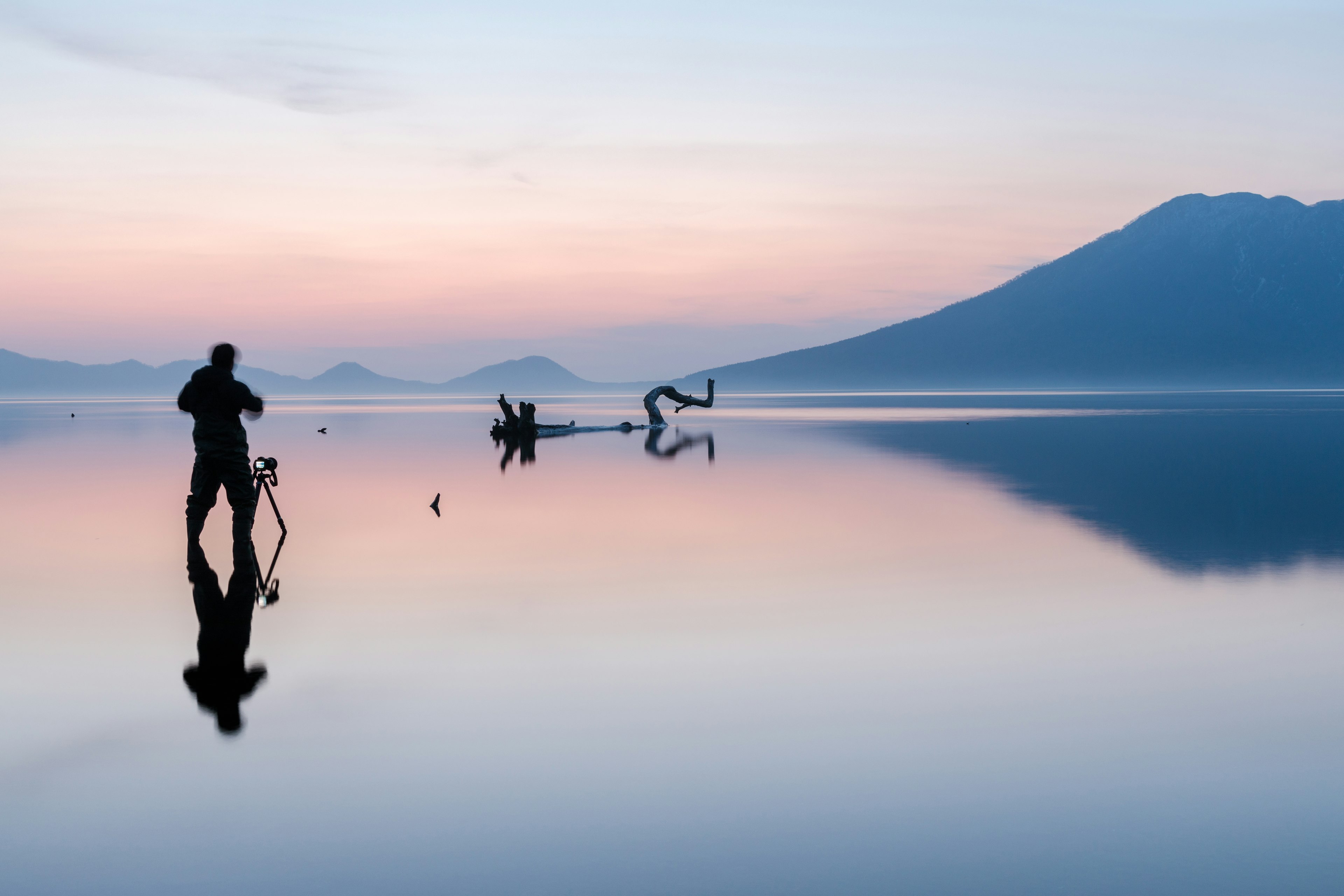 静かな湖で写真を撮る人のシルエットと美しい朝焼けの風景