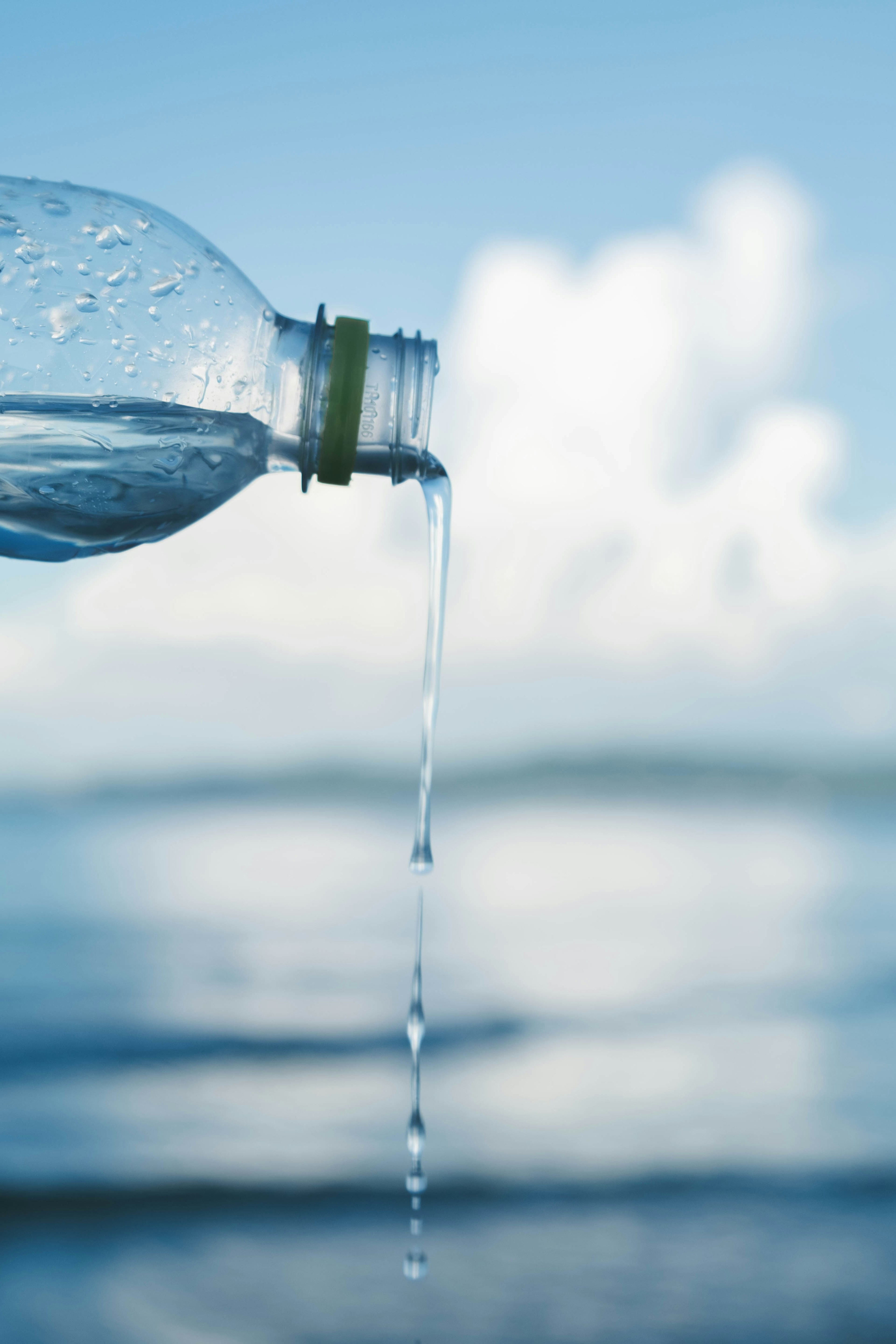 Botella de plástico vertiendo agua cerca del océano