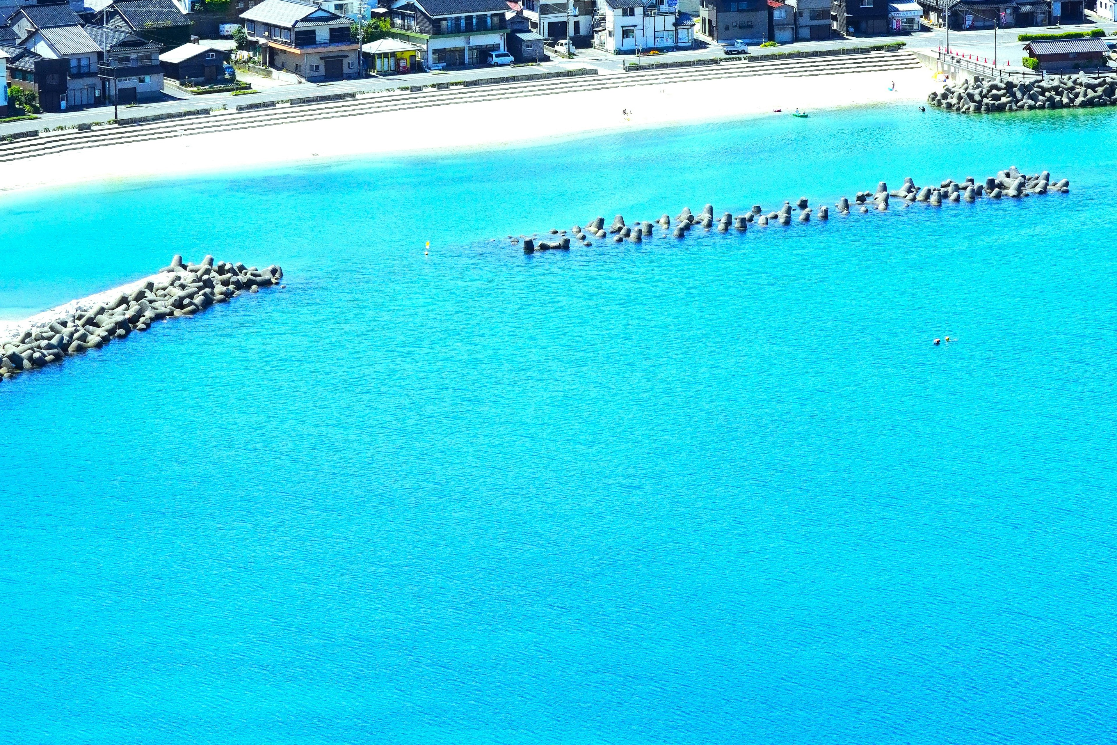 Pemandangan indah air biru cerah dan pantai berpasir dengan formasi pemecah gelombang