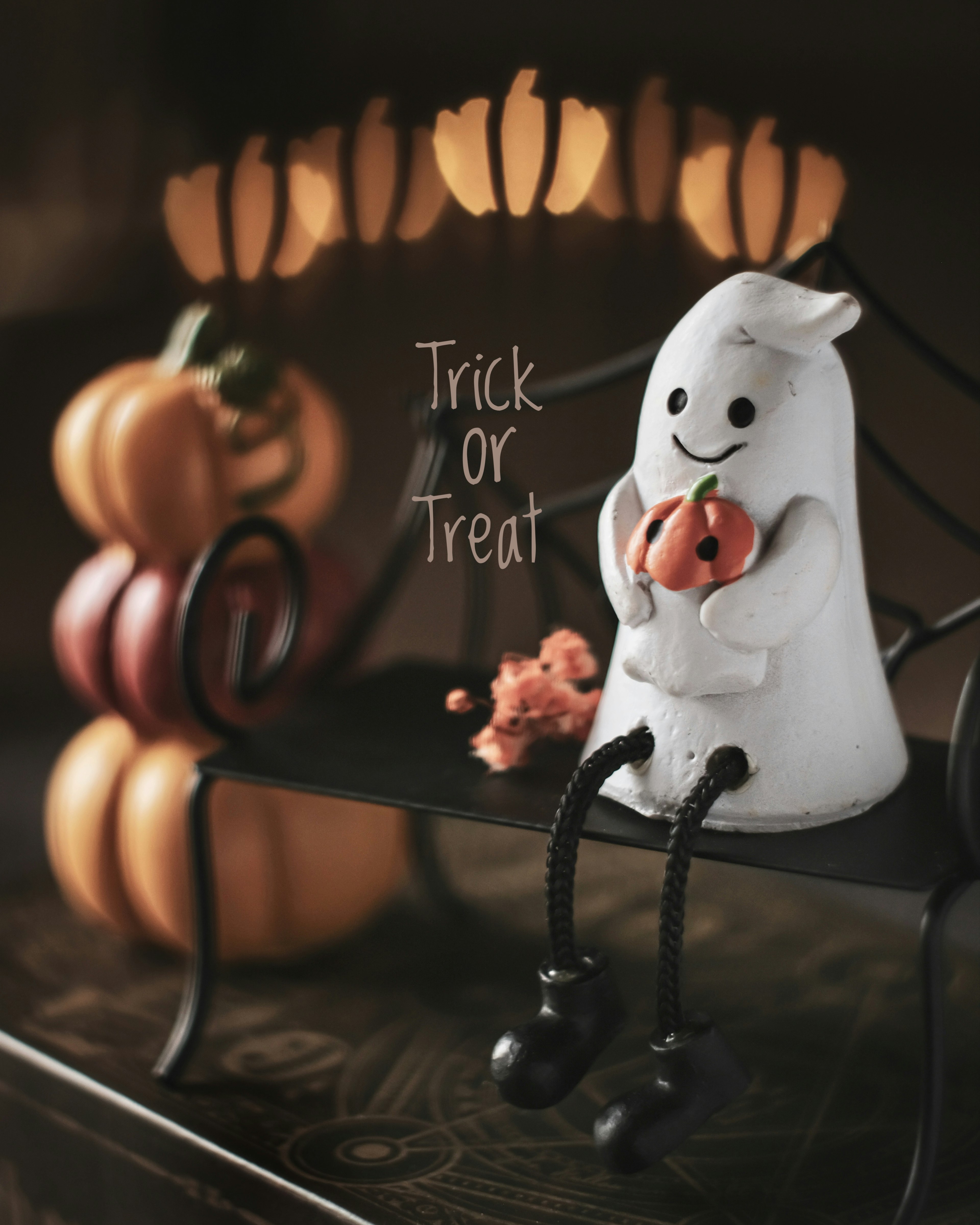 Un personaje espiritual blanco sentado en un banco sosteniendo una calabaza frente a decoraciones de Halloween