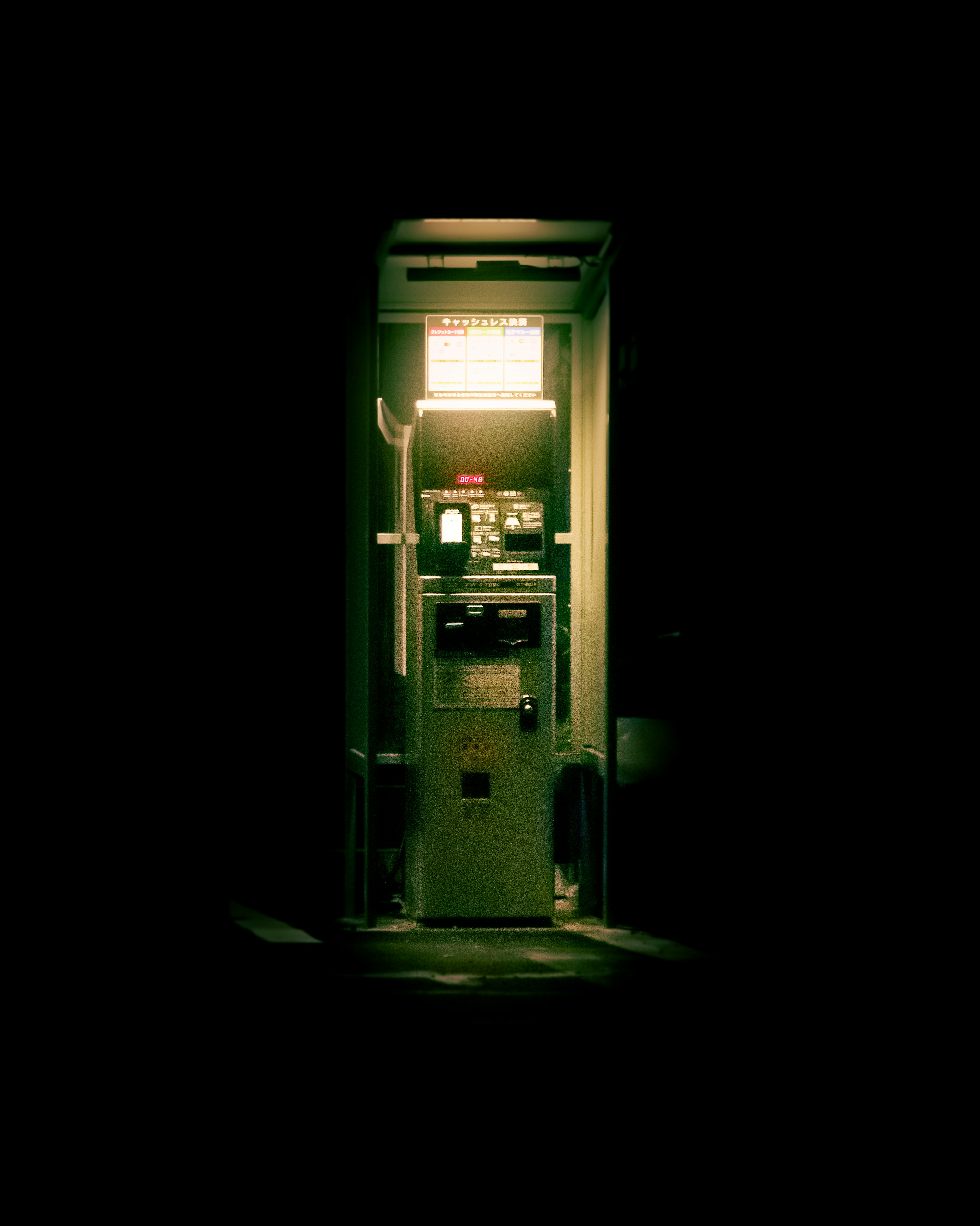 An old phone booth standing in a dim environment with a bright interior