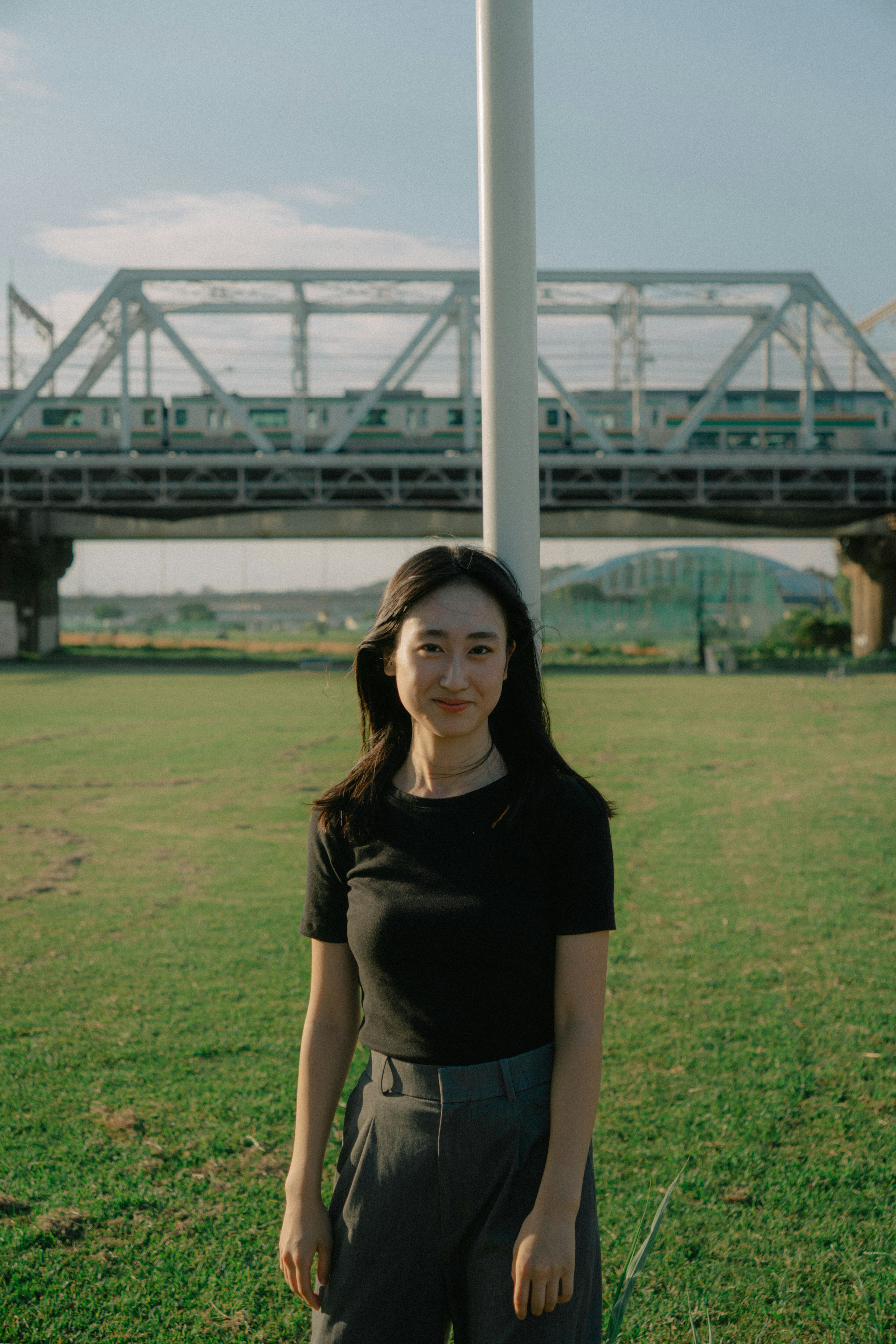 Woman standing in a park with a bridge in the background