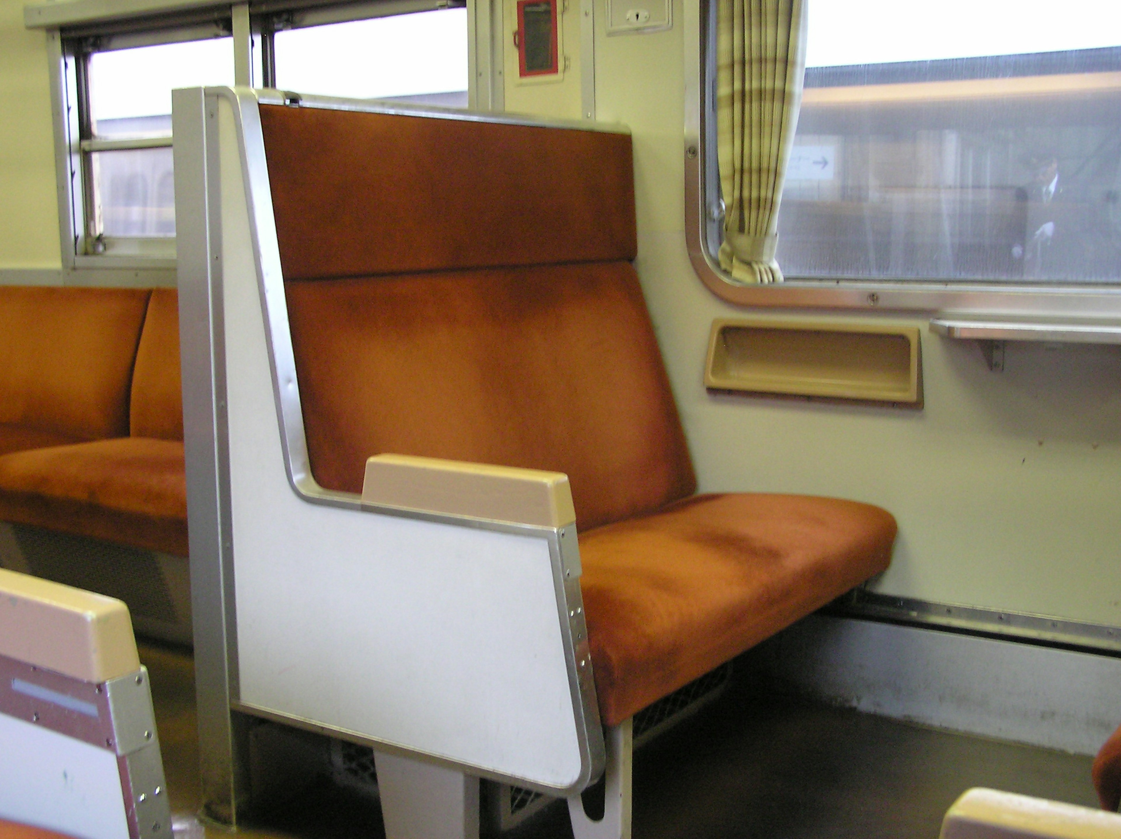 Vista interior de un tren con un asiento tapizado marrón