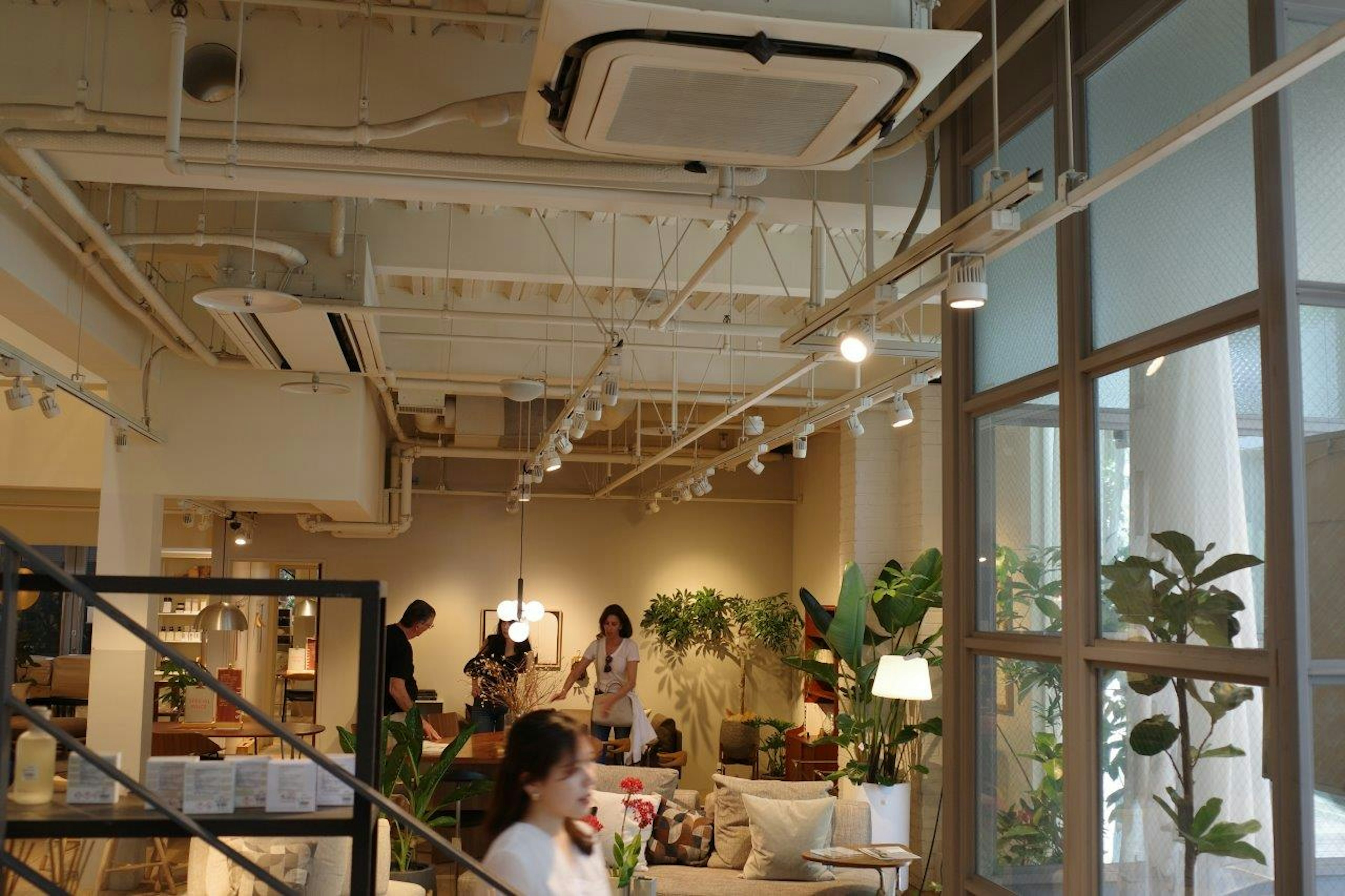 Bright interior of a café with people relaxing surrounded by plants and sofas