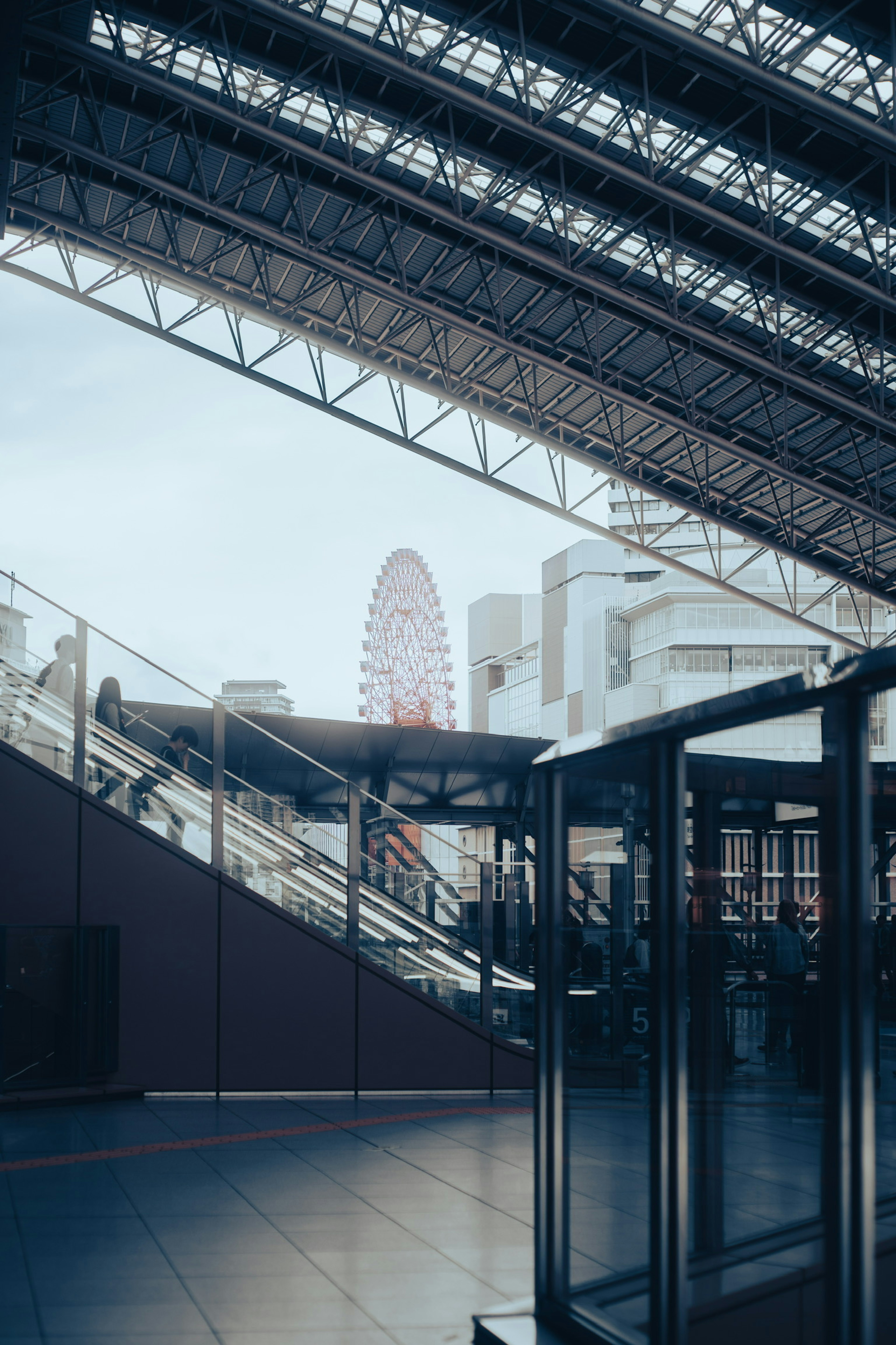 View of a ferris wheel through a modern building's interior and roof structure