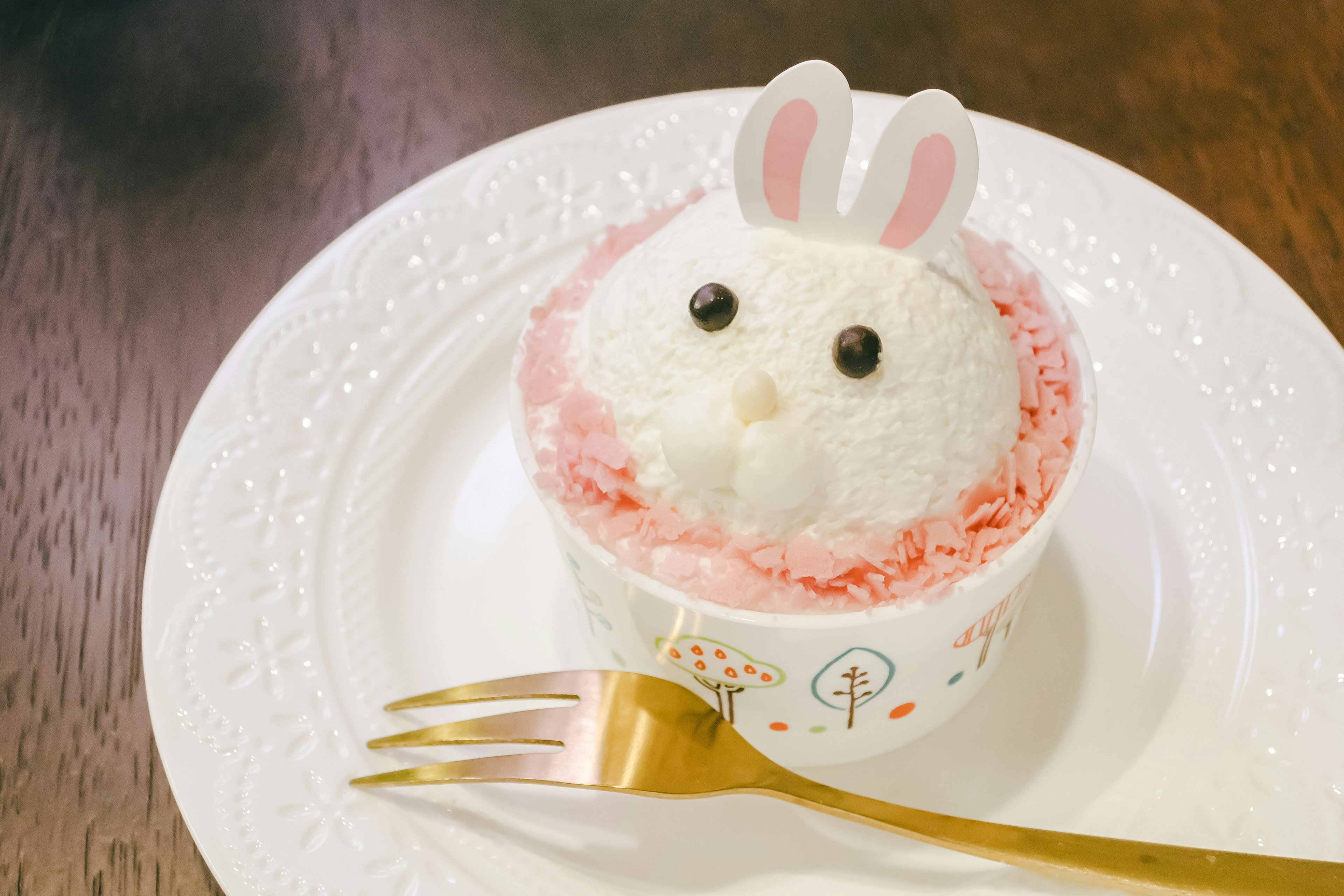 Dessert carino a forma di coniglio con crema rosa che circonda una parte di riso bianco e cioccolato per gli occhi