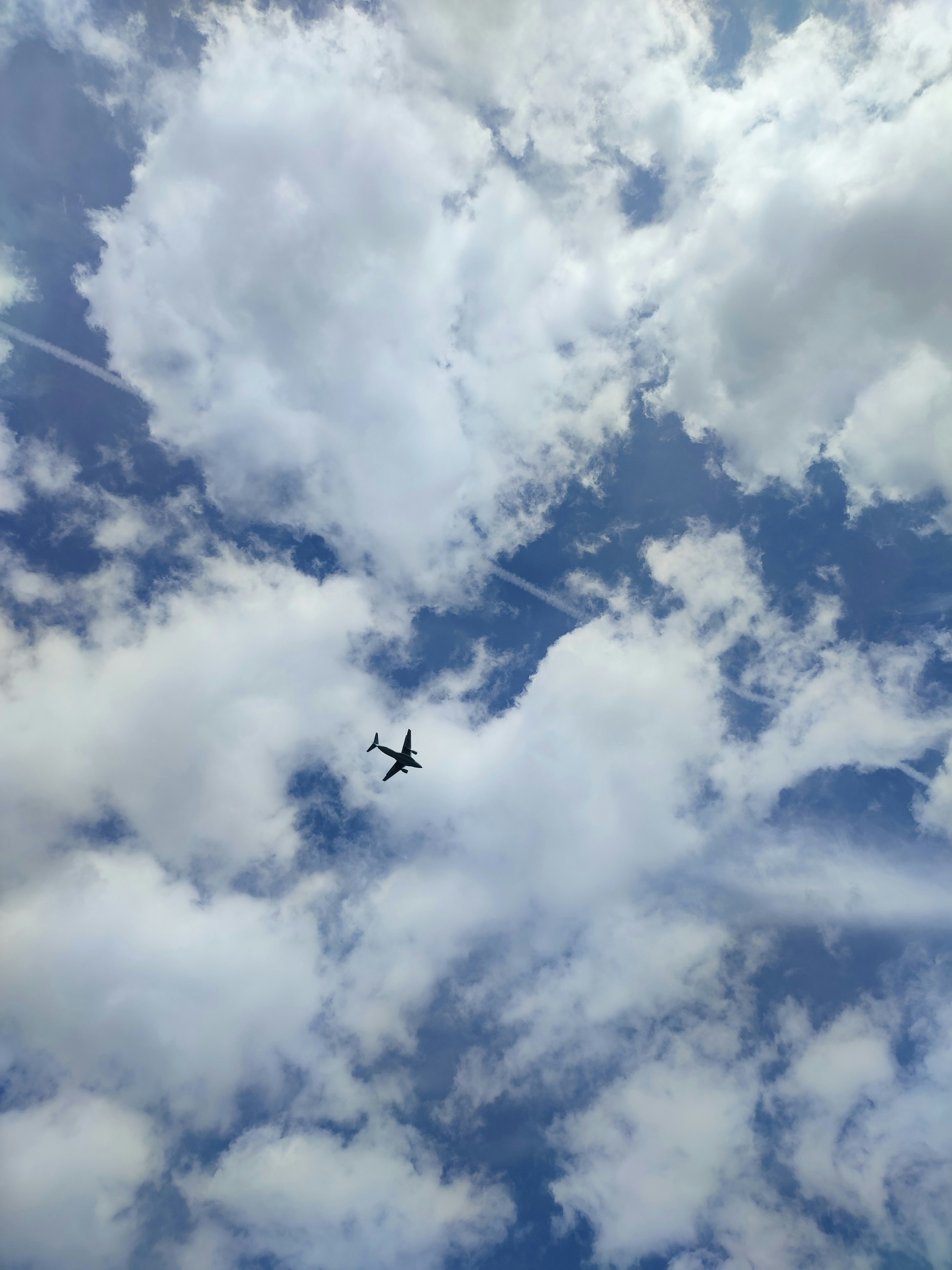 Un avión volando en un cielo azul con nubes blancas