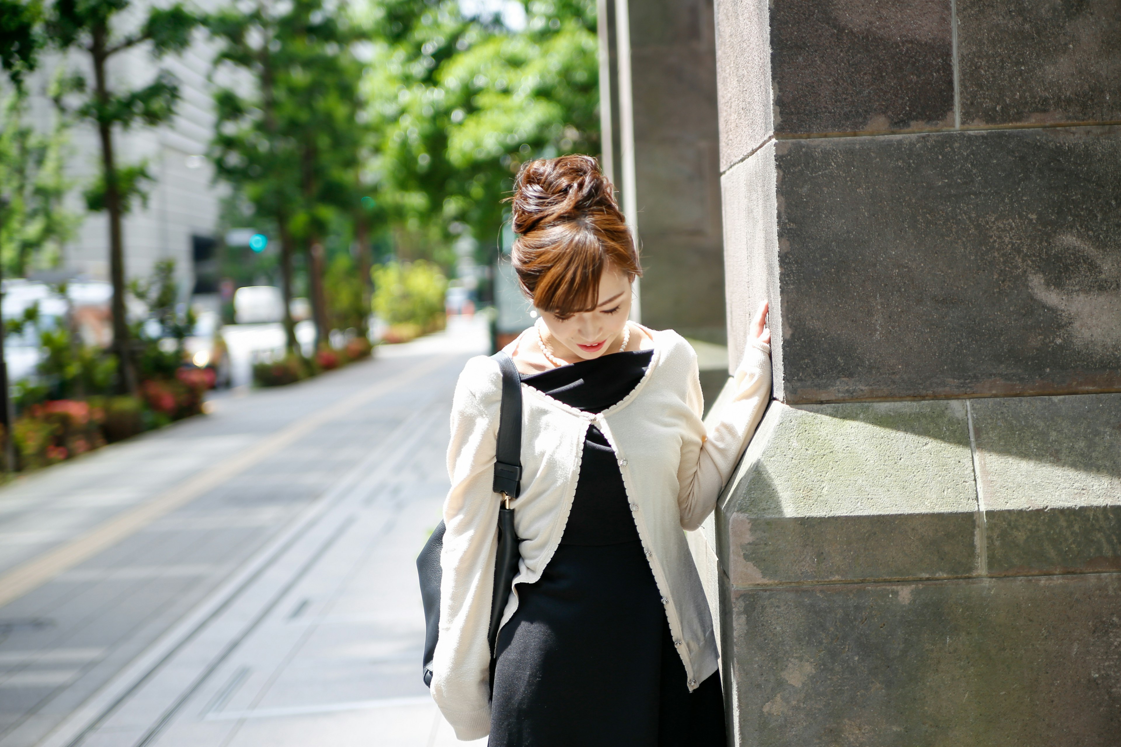 一位女性靠在城市中的墙上