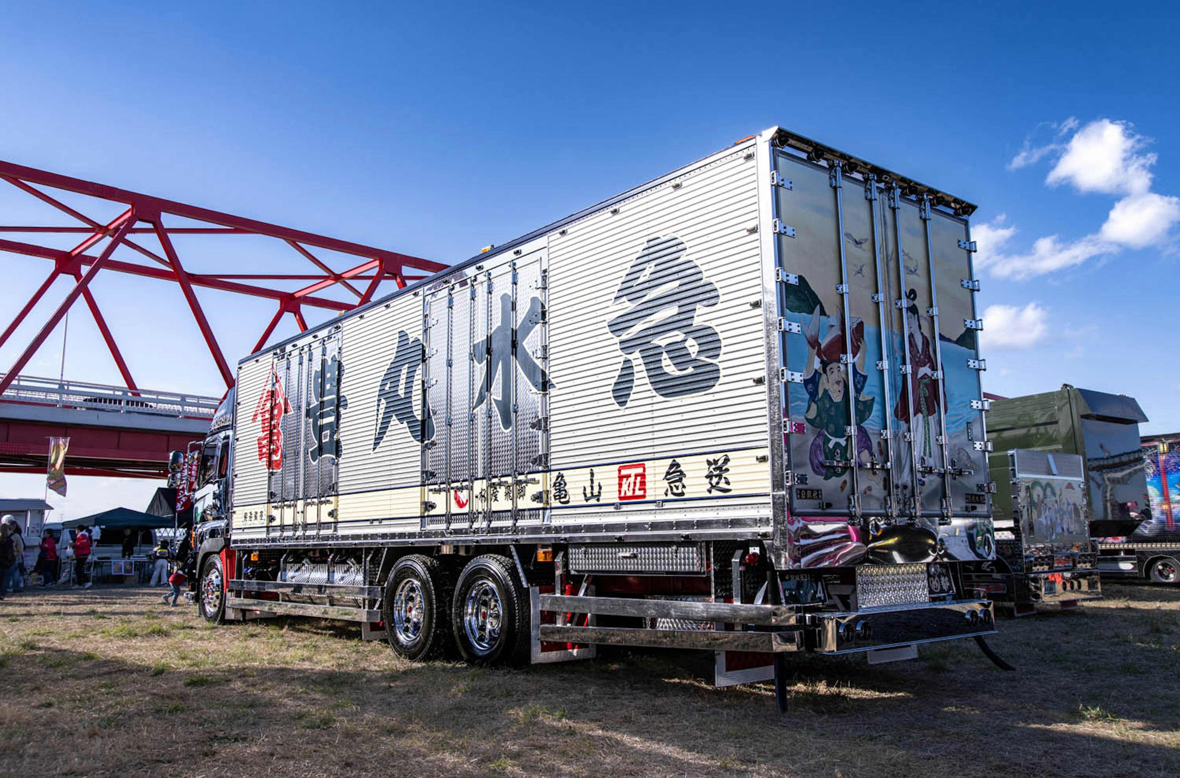 A truck with large Japanese text and colorful artwork on its rear side