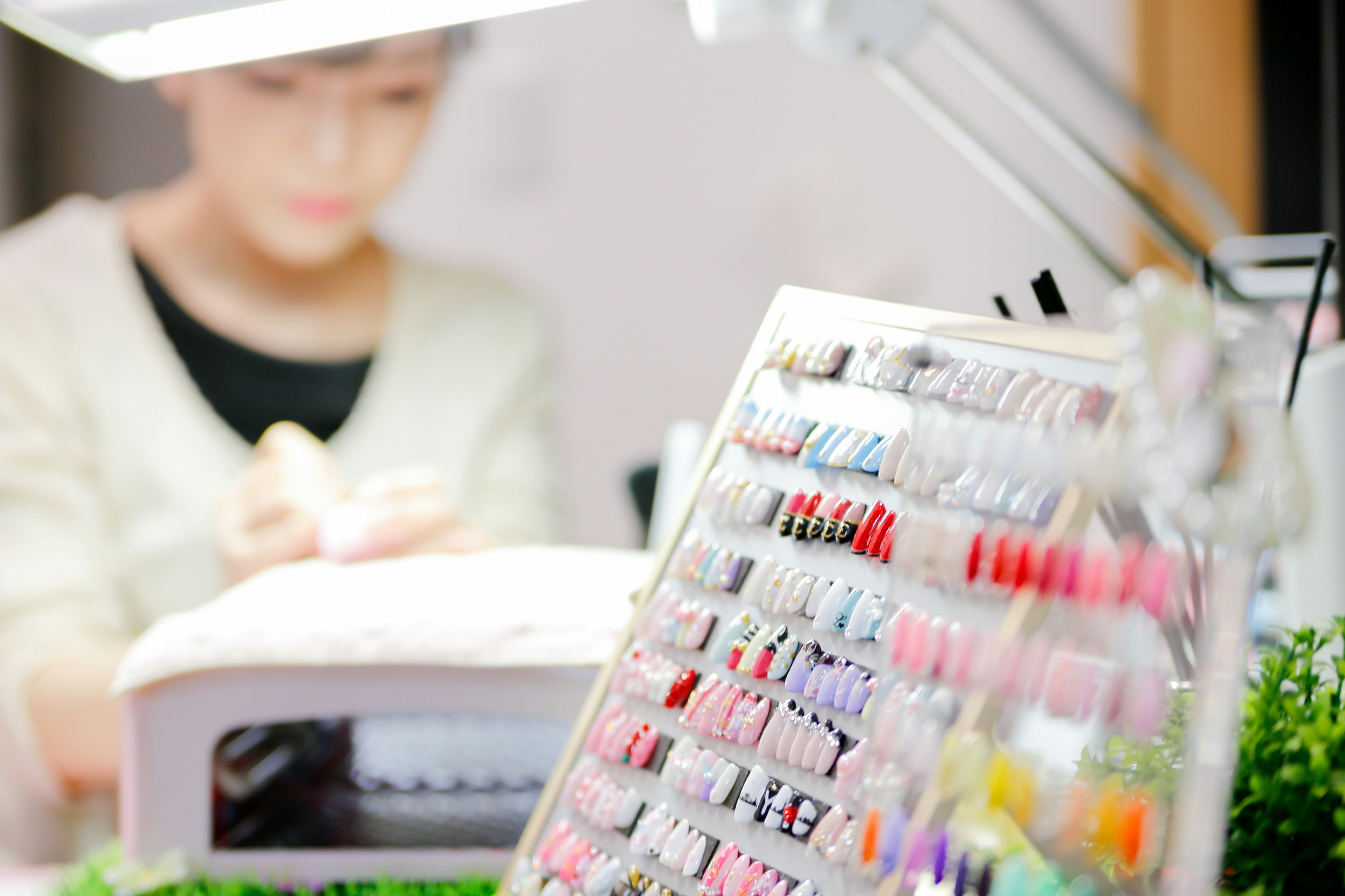 Mujer trabajando en un salón de uñas con botellas de esmalte de uñas coloridas