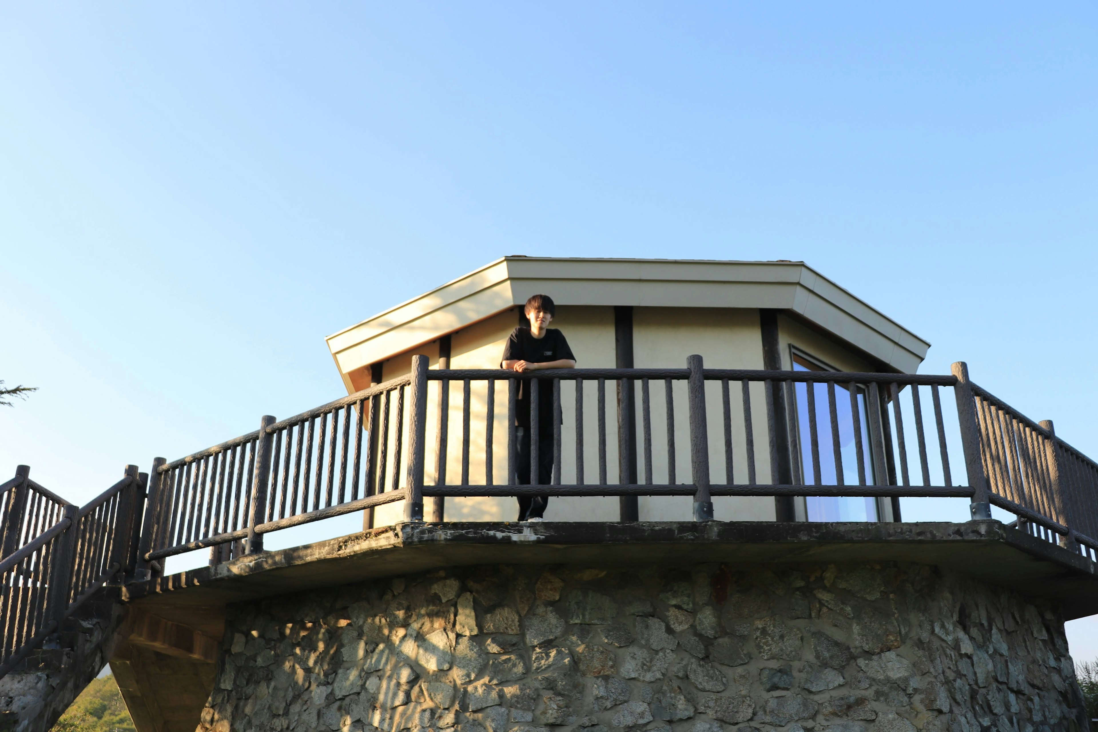 Person steht auf einem Steinturm mit einer achteckigen Aussichtsplattform