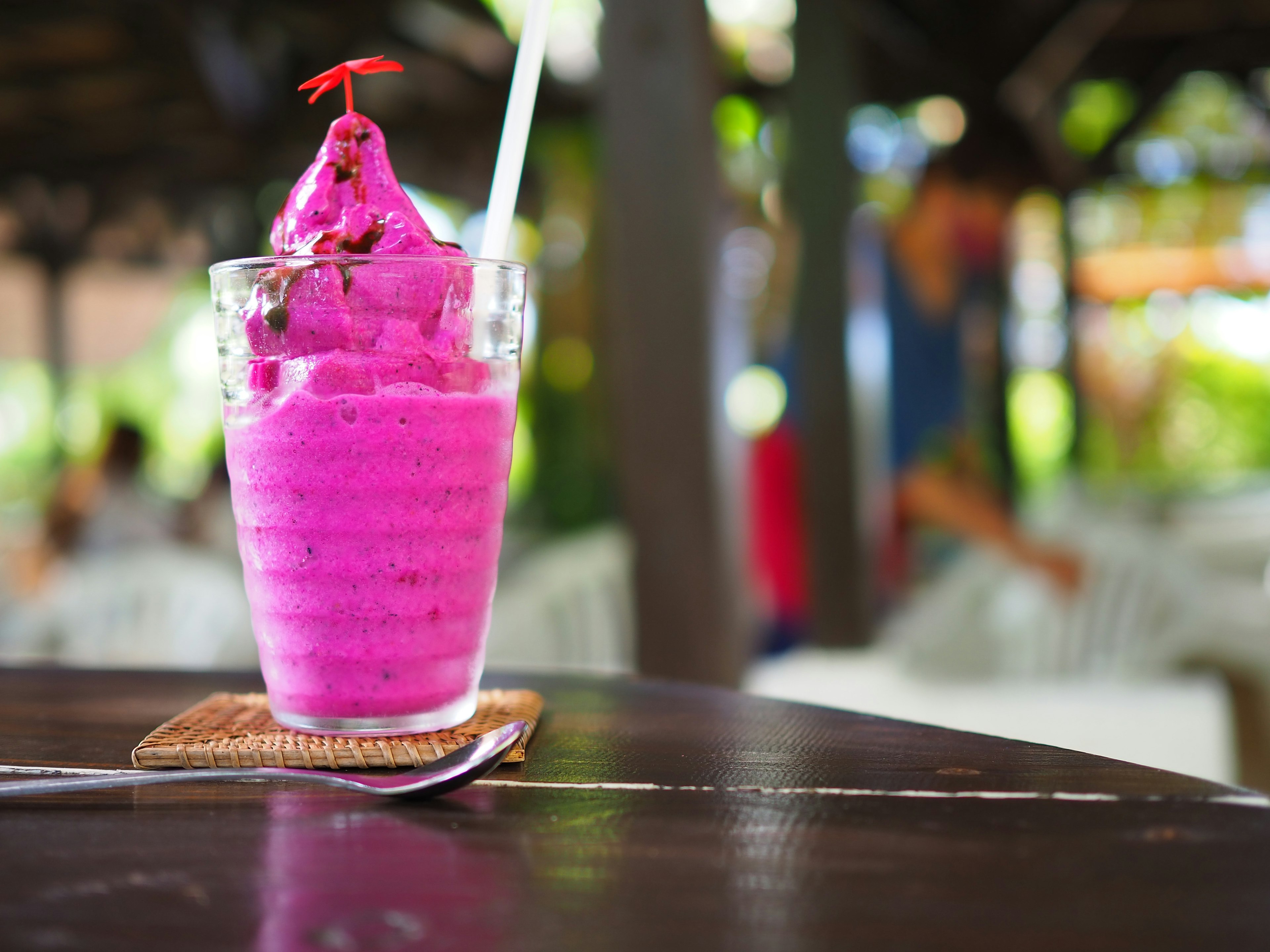 Smoothie merah muda cerah disajikan dalam gelas dengan topping ceri merah