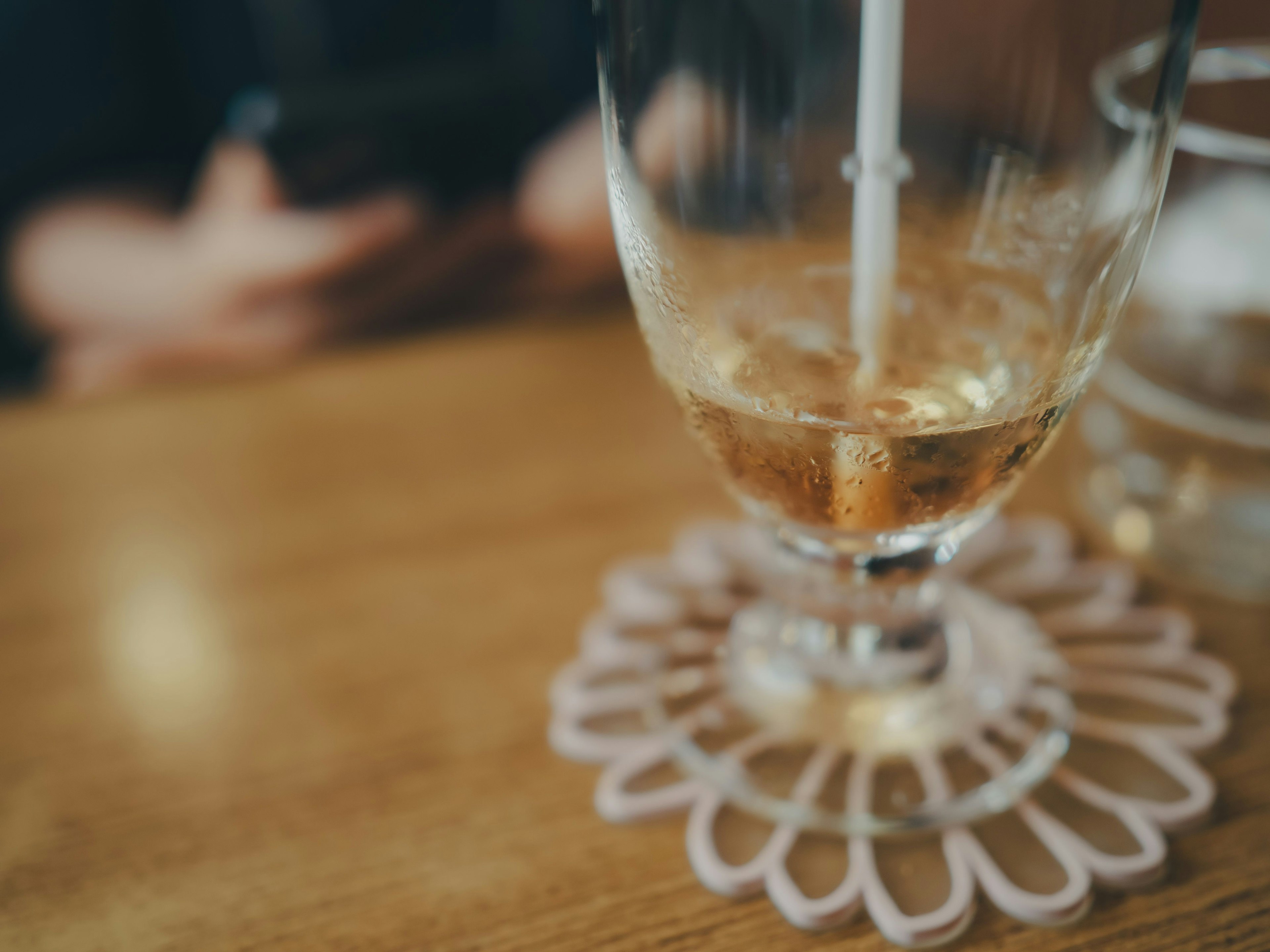 Ein transparentes Glas mit einem Getränk auf einem Holztisch mit einem dekorativen Untersetzer