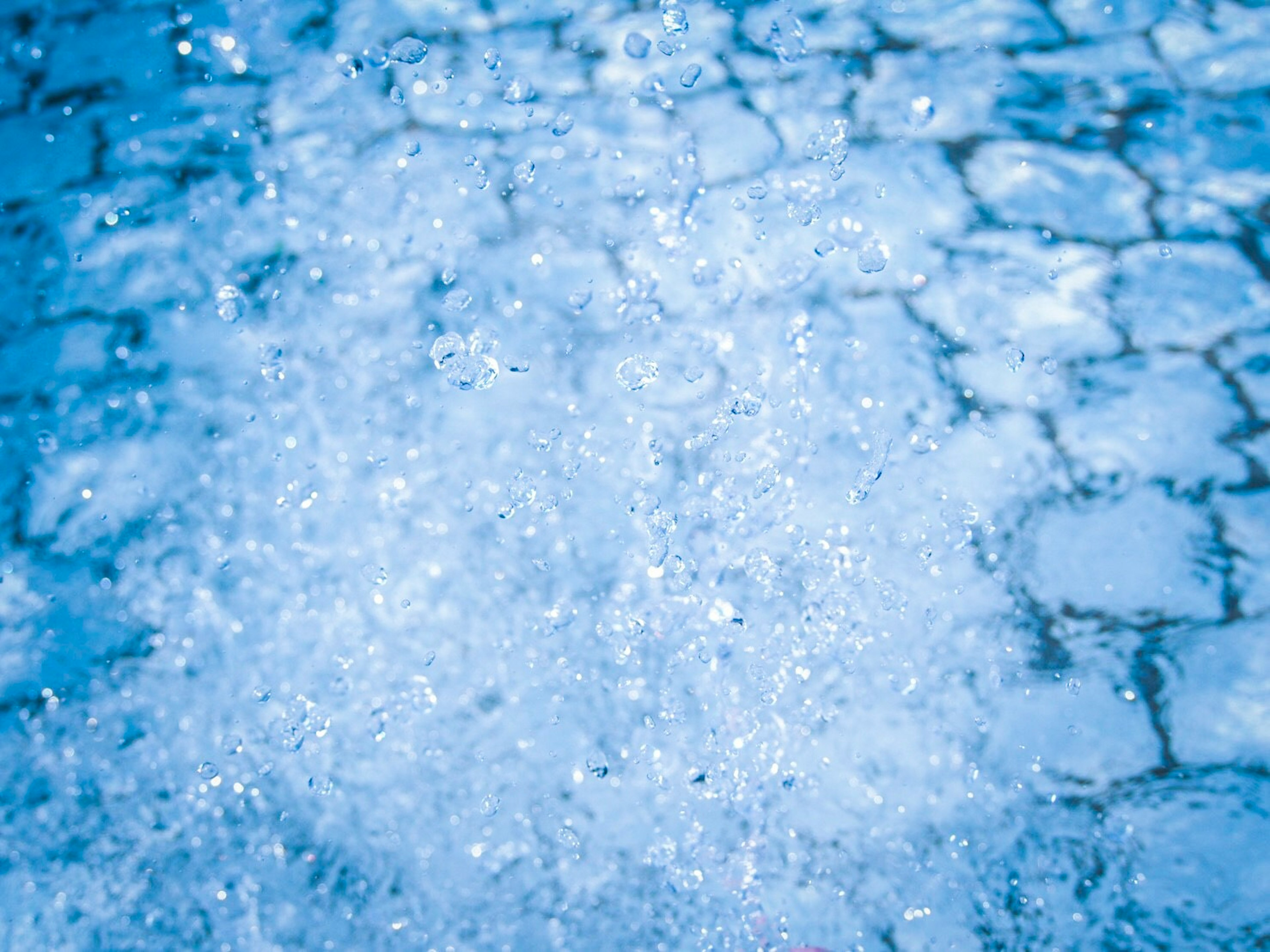 Bild von Wasseroberfläche mit blauen Reflexionen und Blasen