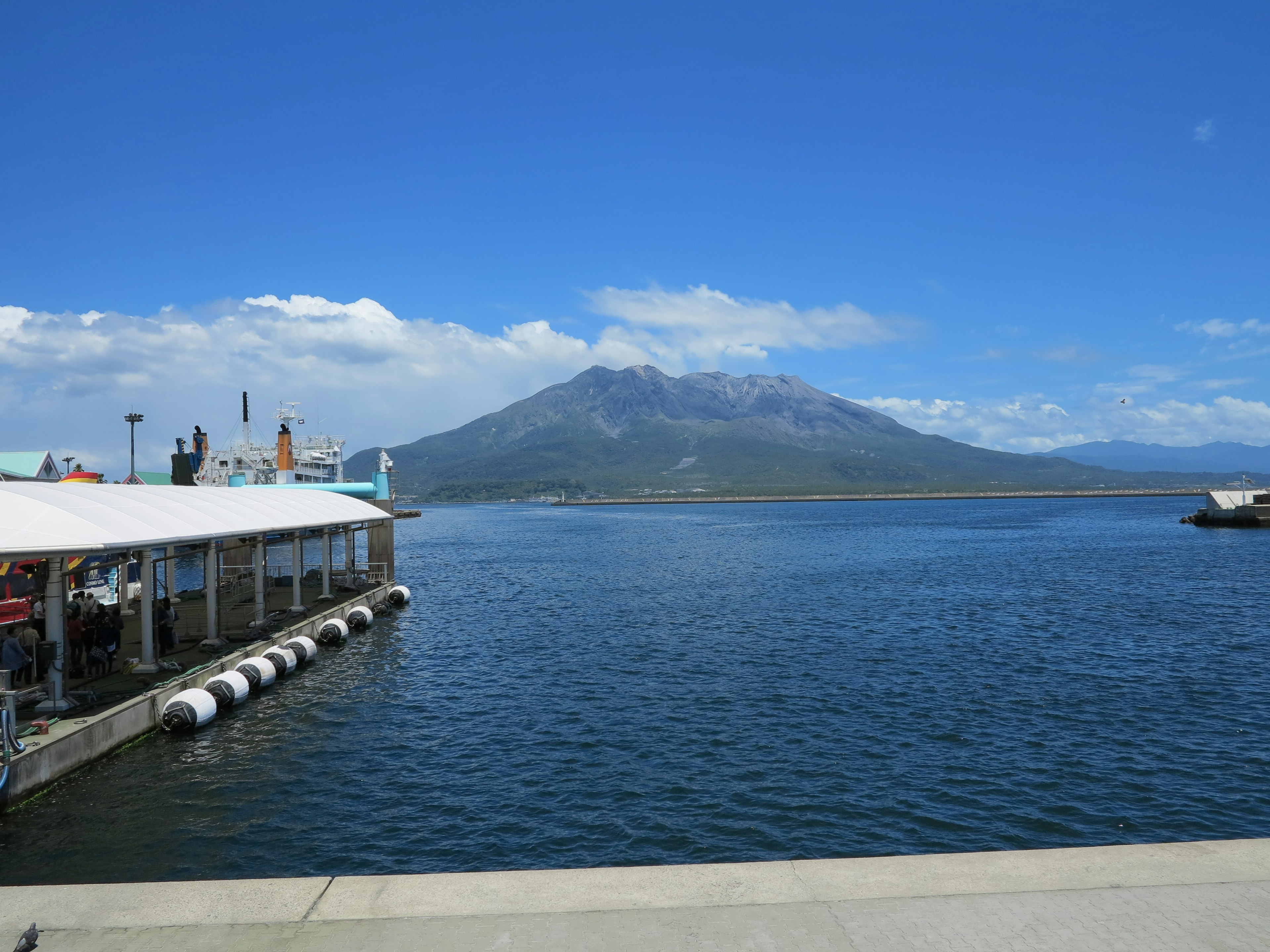 ทิวทัศน์ที่สวยงามของภูเขาไฟที่ตั้งตระหง่านเหนือทะเลสาบสีน้ำเงินใต้ท้องฟ้าที่แจ่มใส