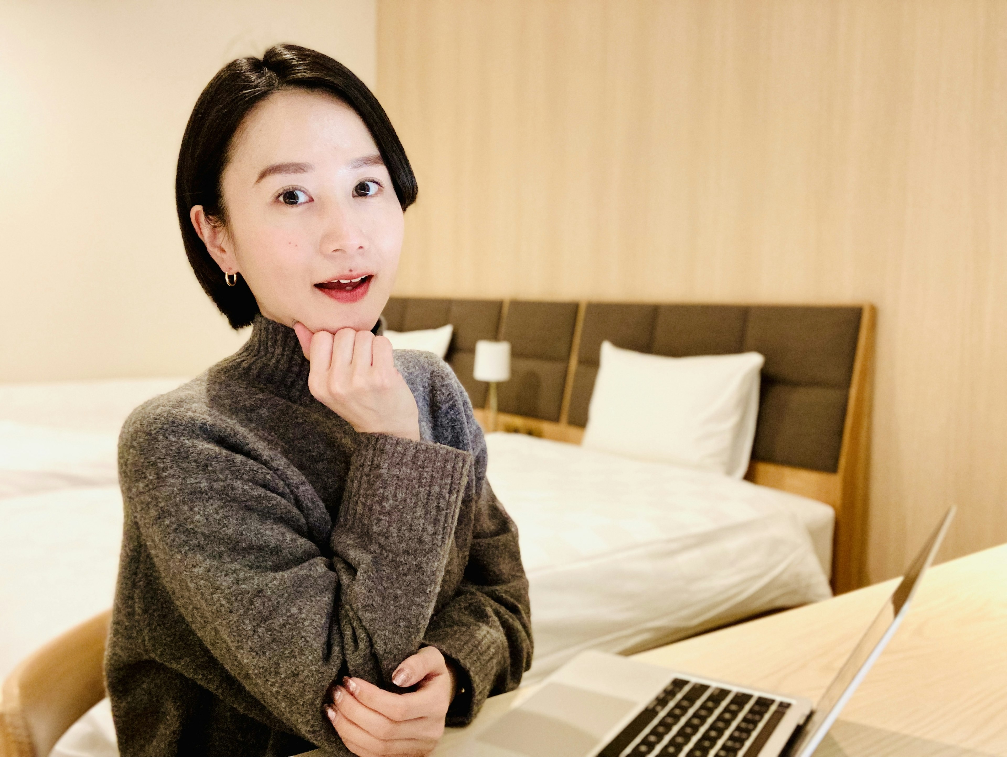 Young woman smiling while using a laptop in a room with beds