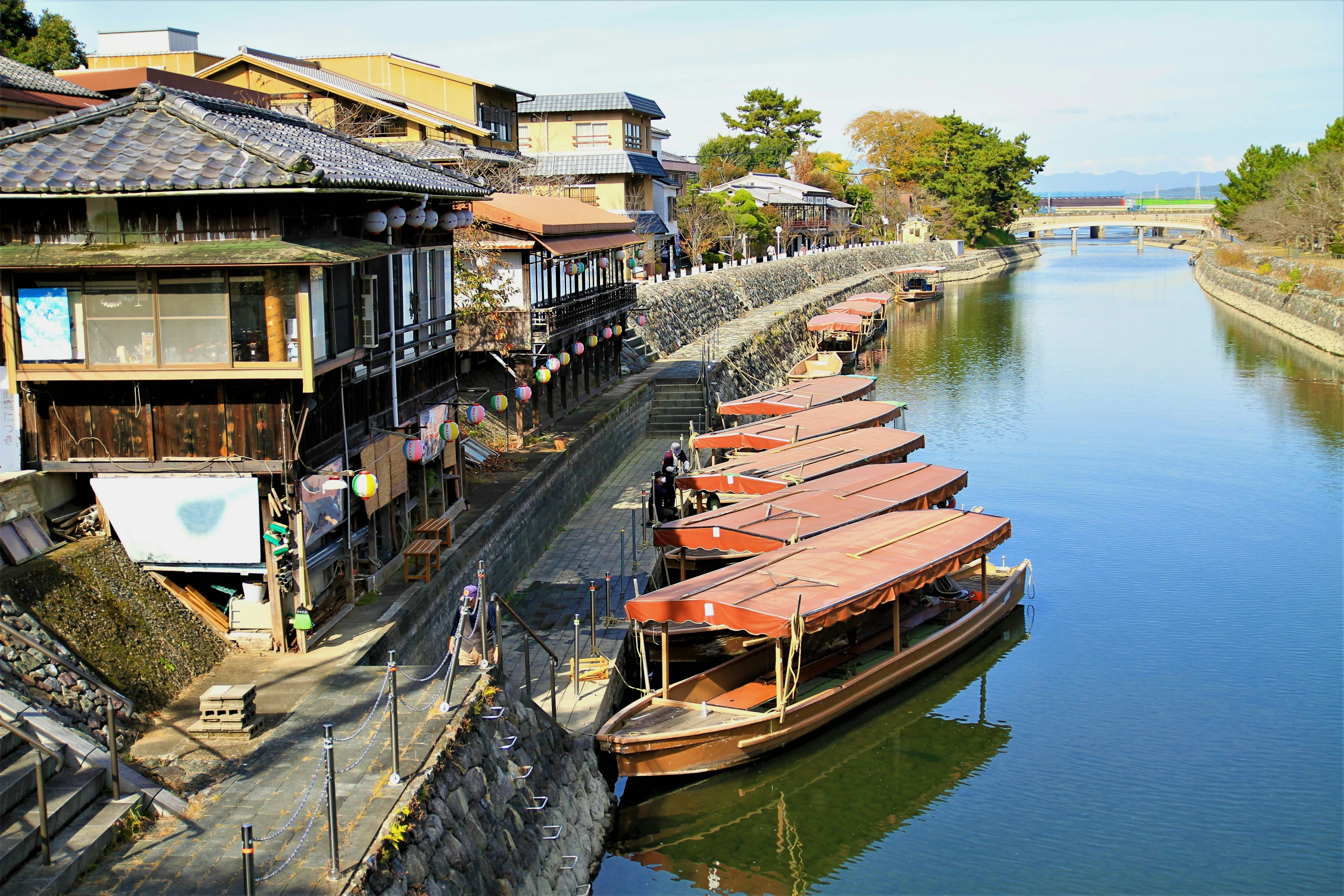 Vista escénica de botes tradicionales alineados a lo largo de un río con edificios históricos