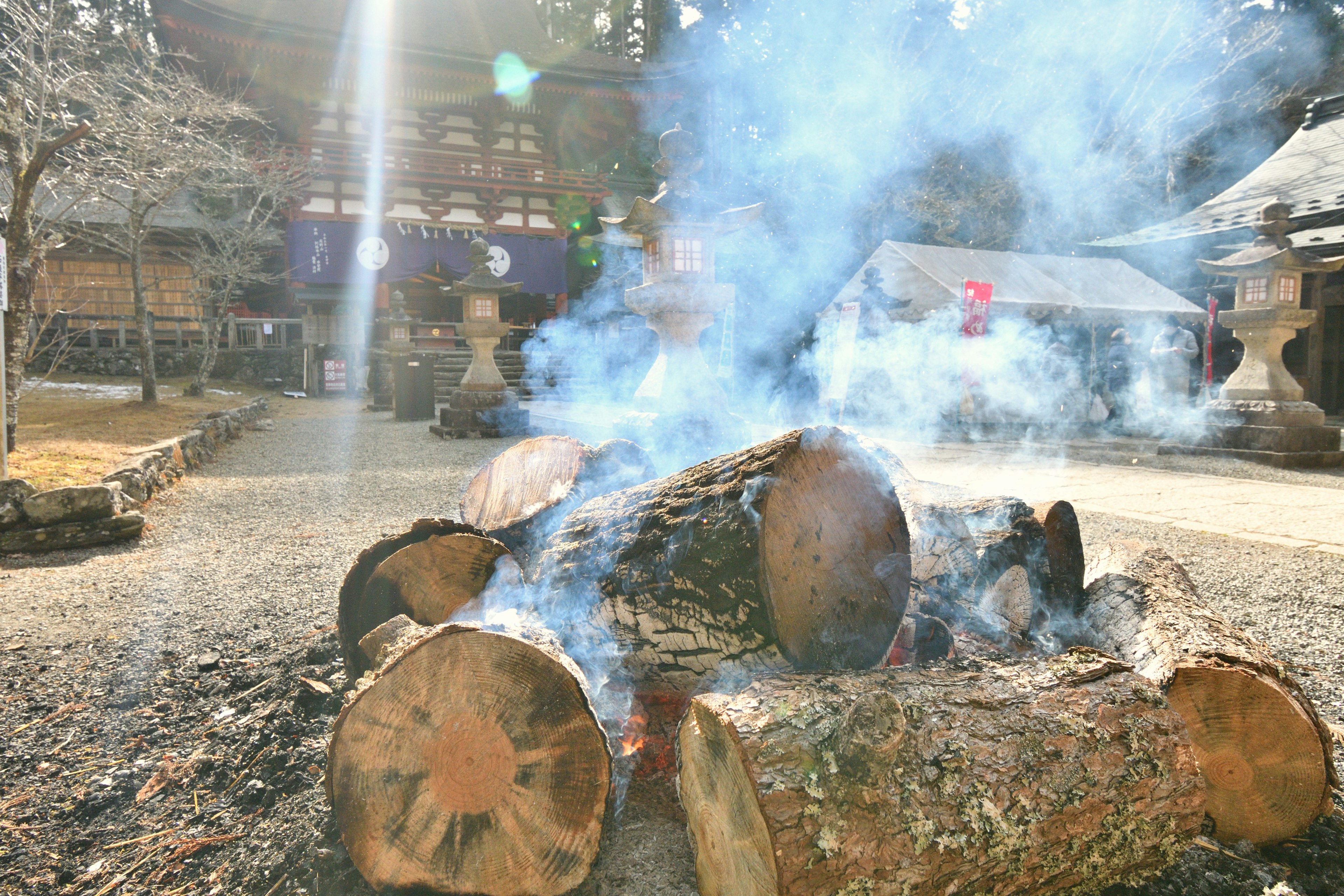 Brennende Holzscheite, die Rauch erzeugen, mit Gebäuden im Hintergrund