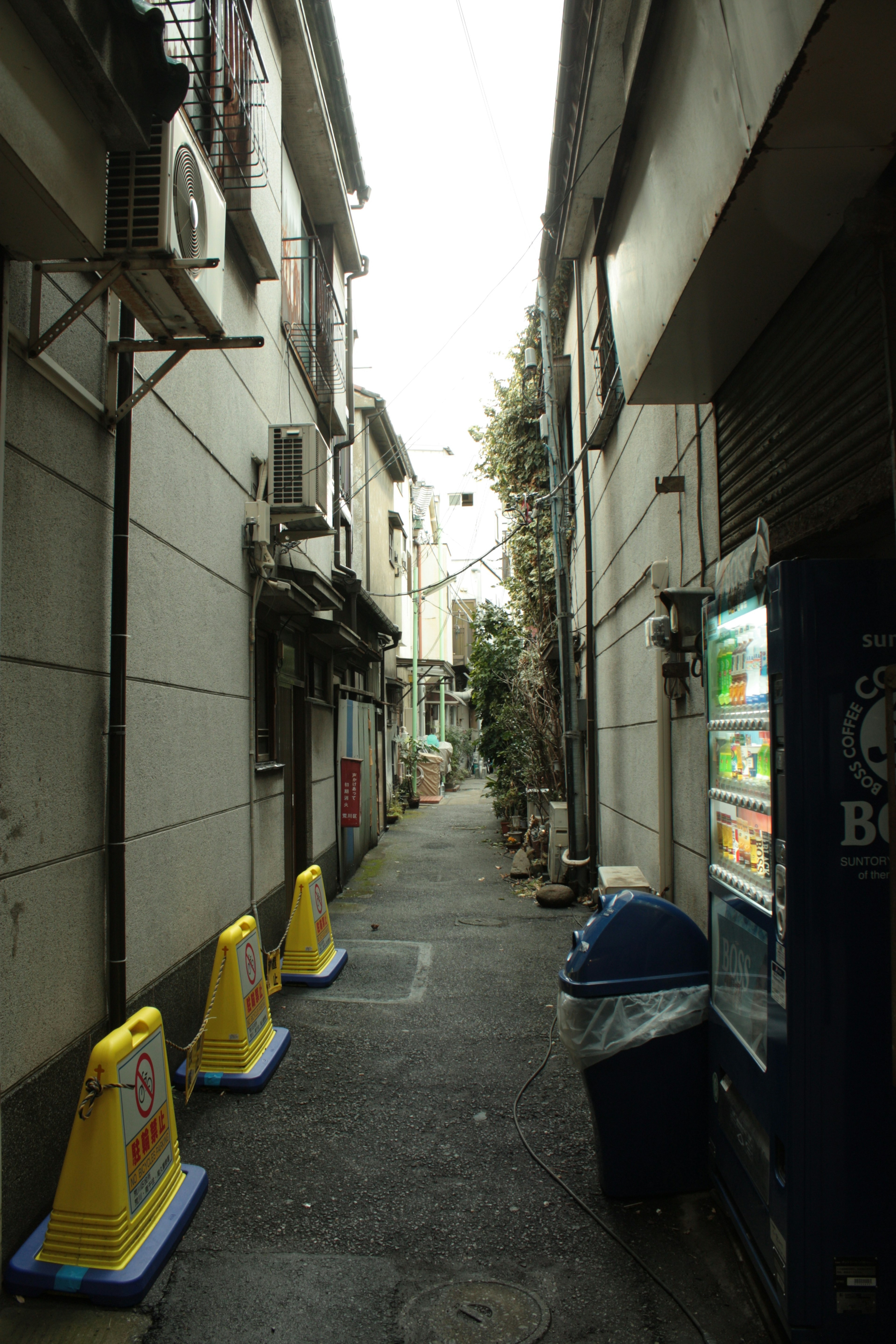 Callejón estrecho con edificios y una máquina expendedora