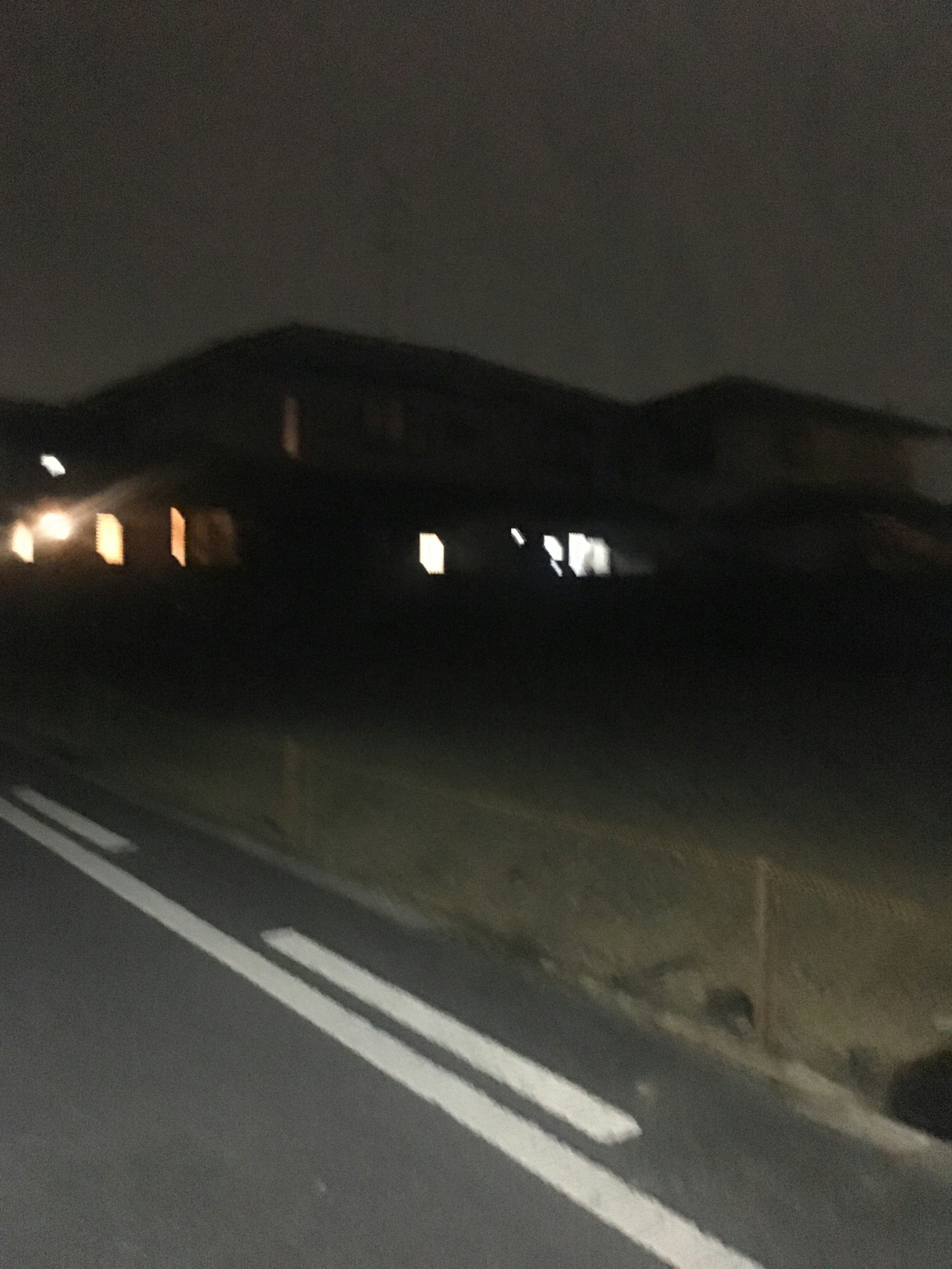 Escena nocturna oscura de un área residencial con luz que sale de las ventanas