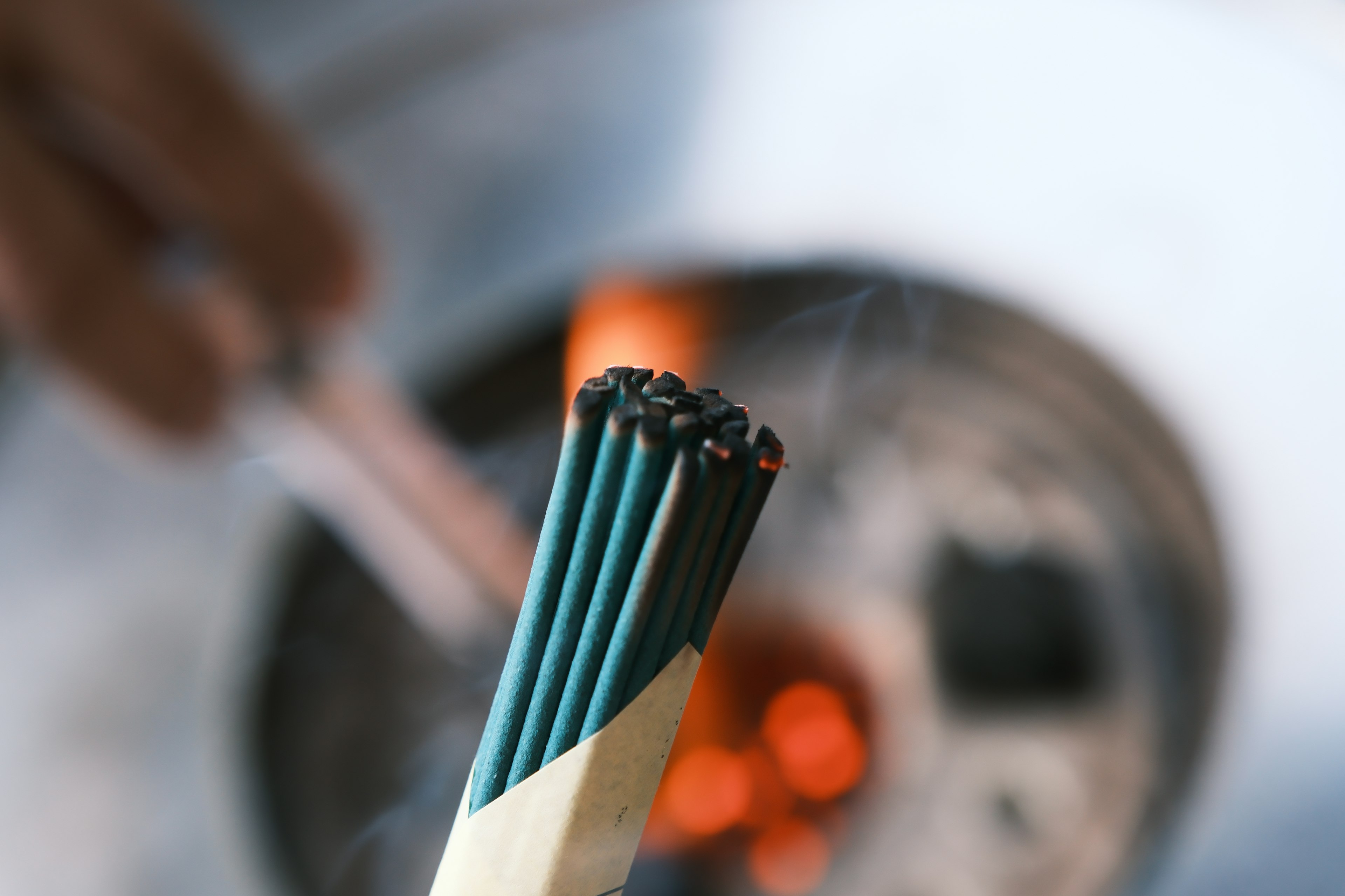 A bundle of incense sticks held above glowing coals