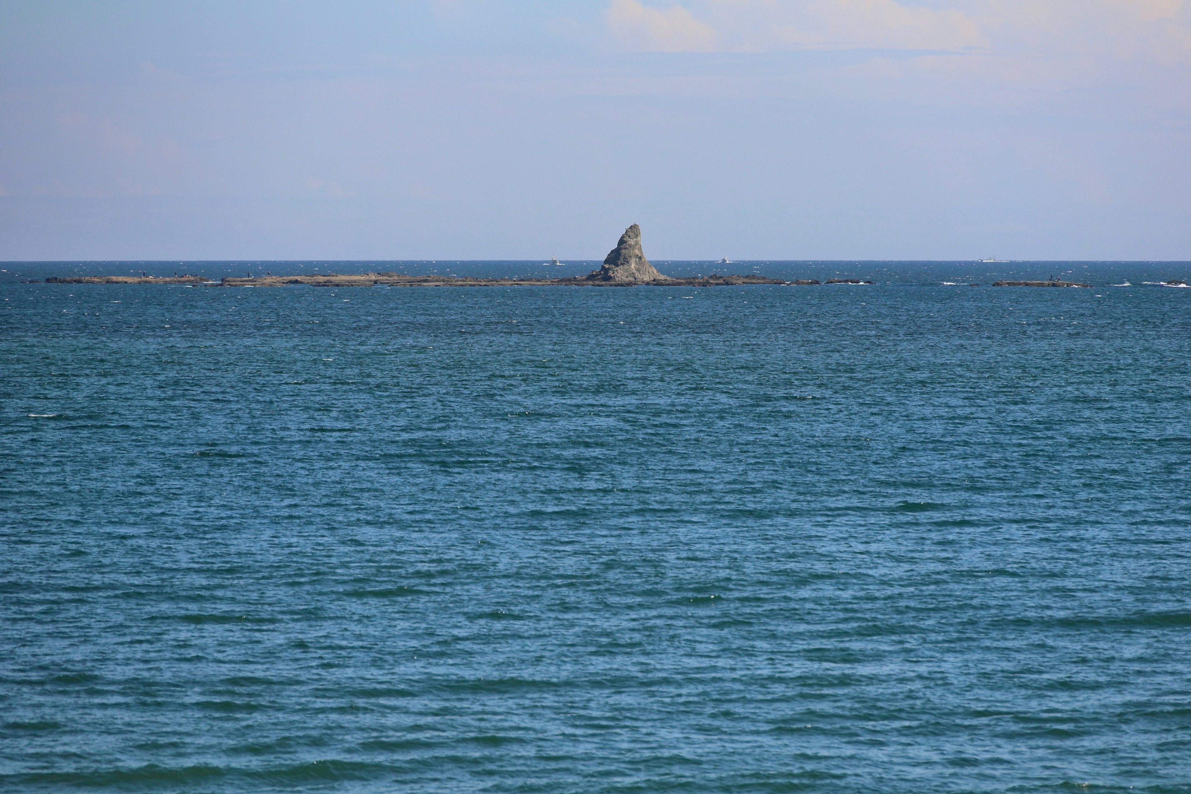 Una formación rocosa afilada visible en un mar azul