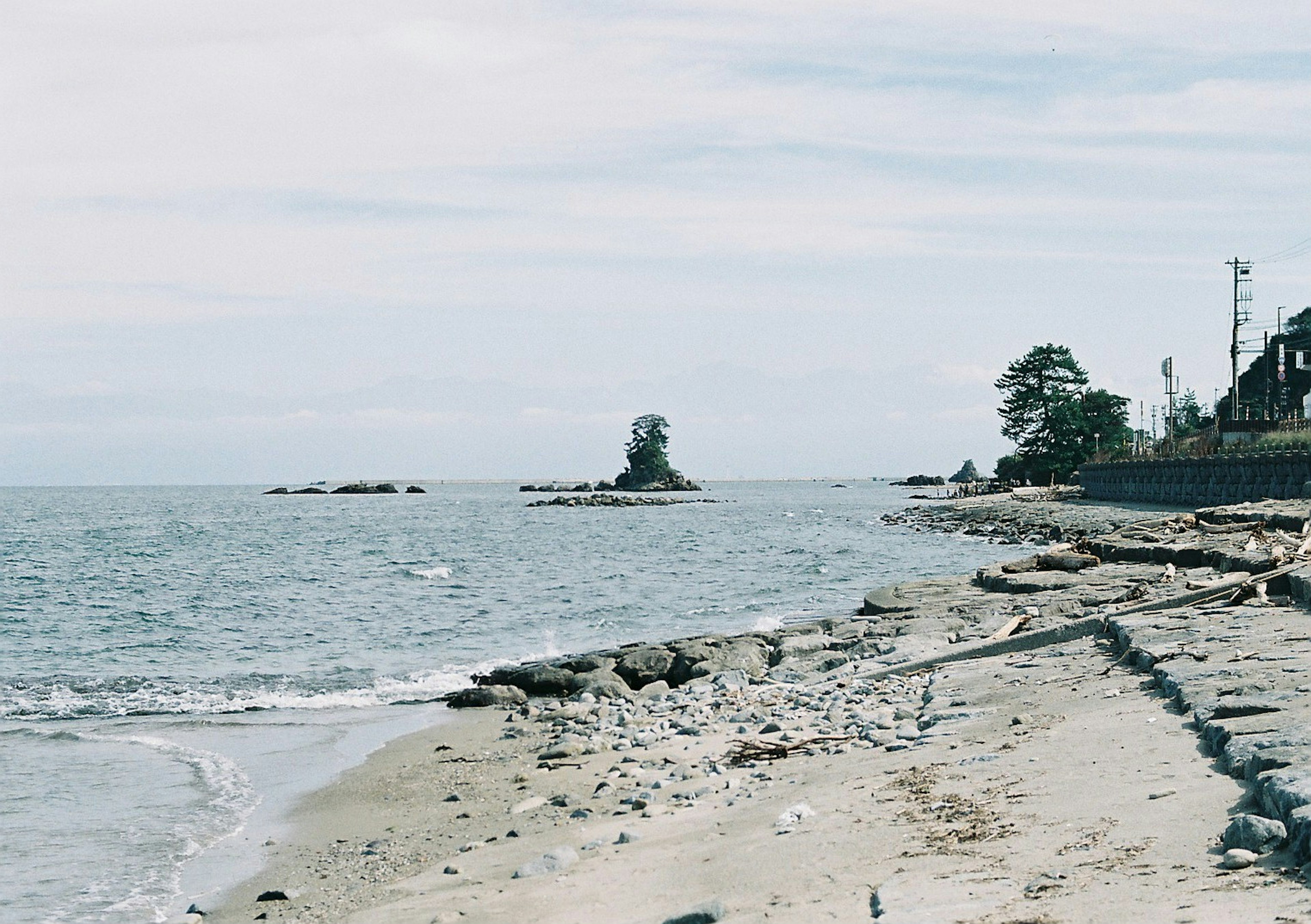 Calm beach scene featuring a coastline and rocky outcrops