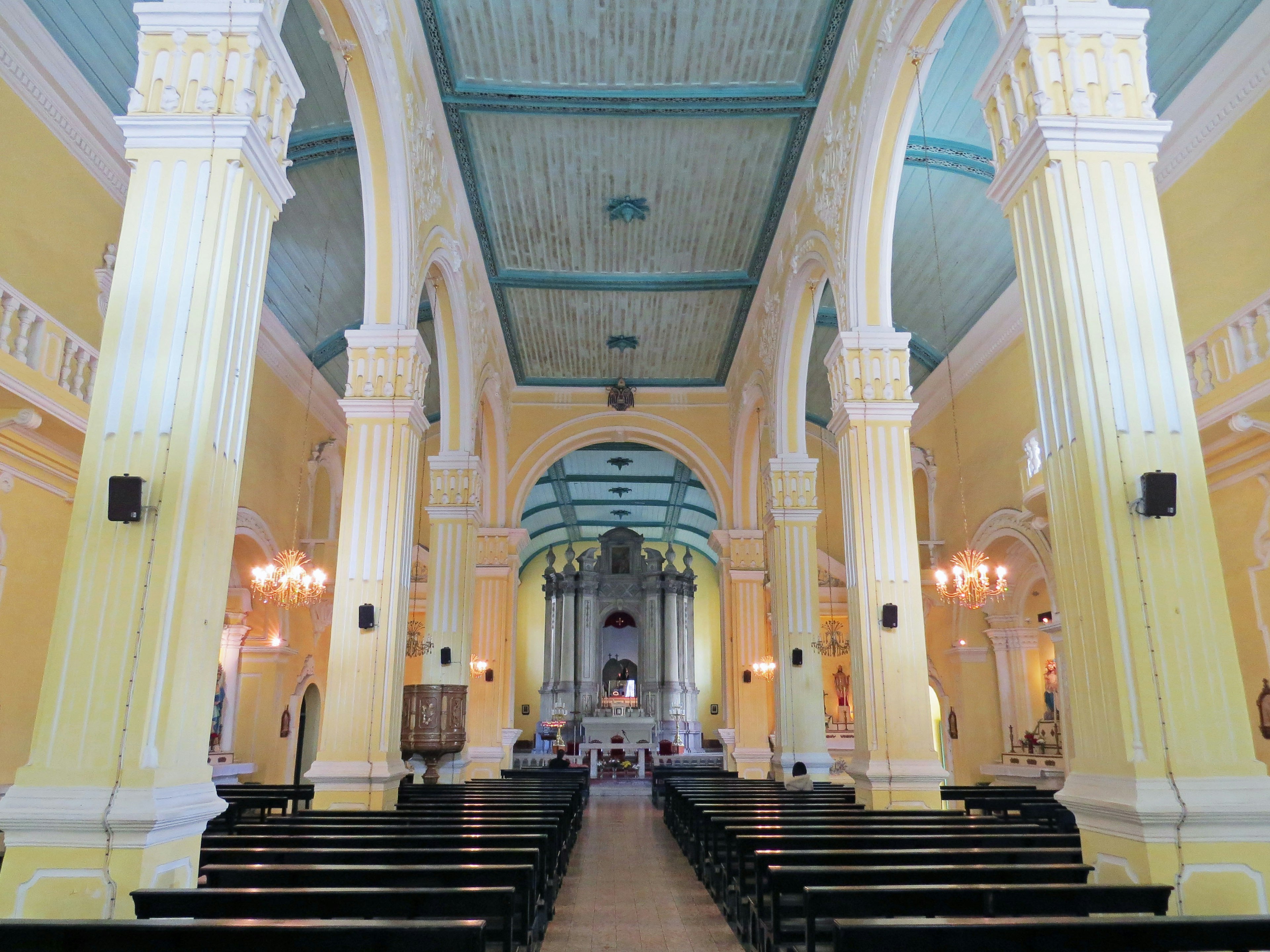 Pemandangan interior gereja dengan dinding kuning cerah dan langit-langit biru