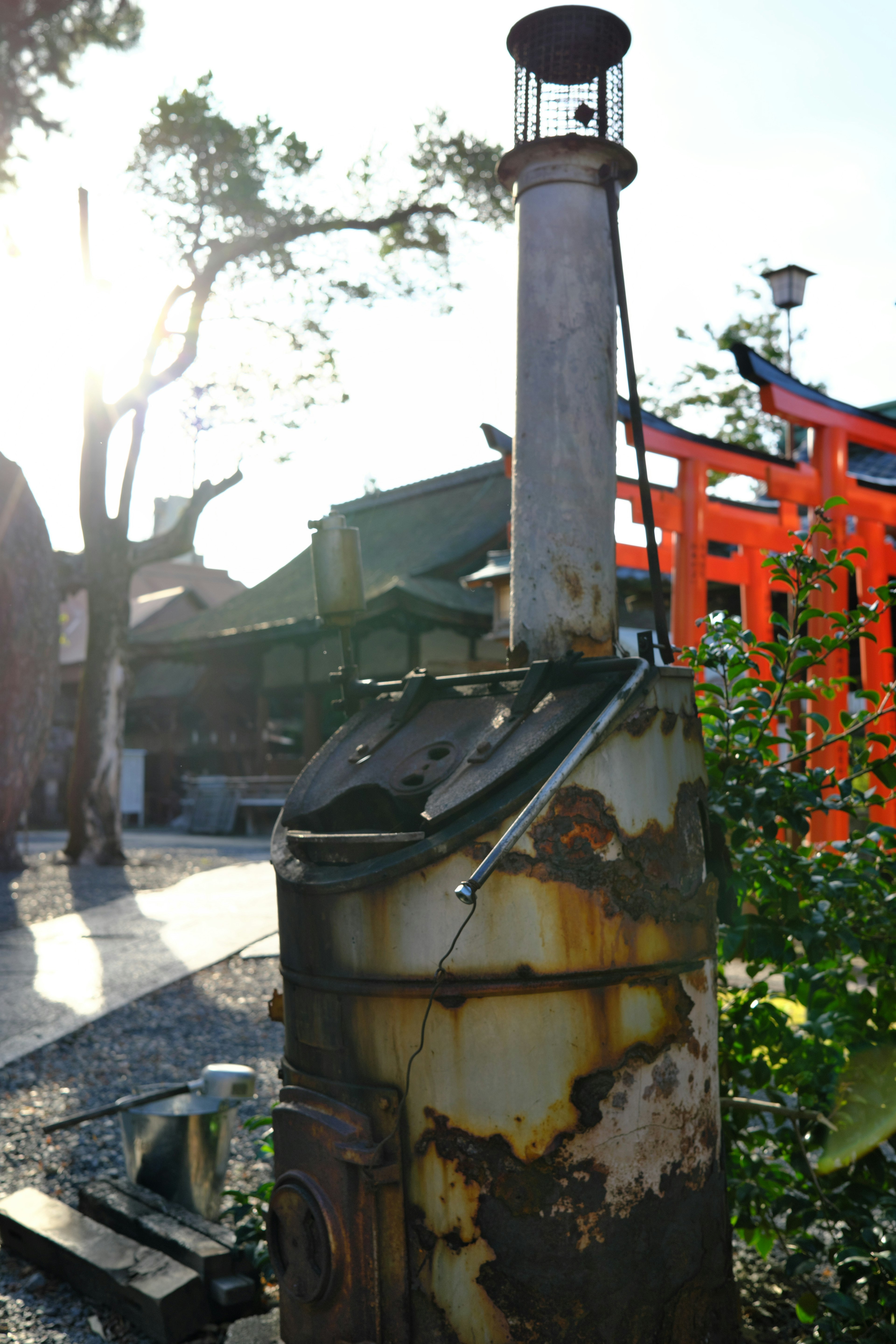 An old chimney-like structure with surrounding red torii gates and green plants