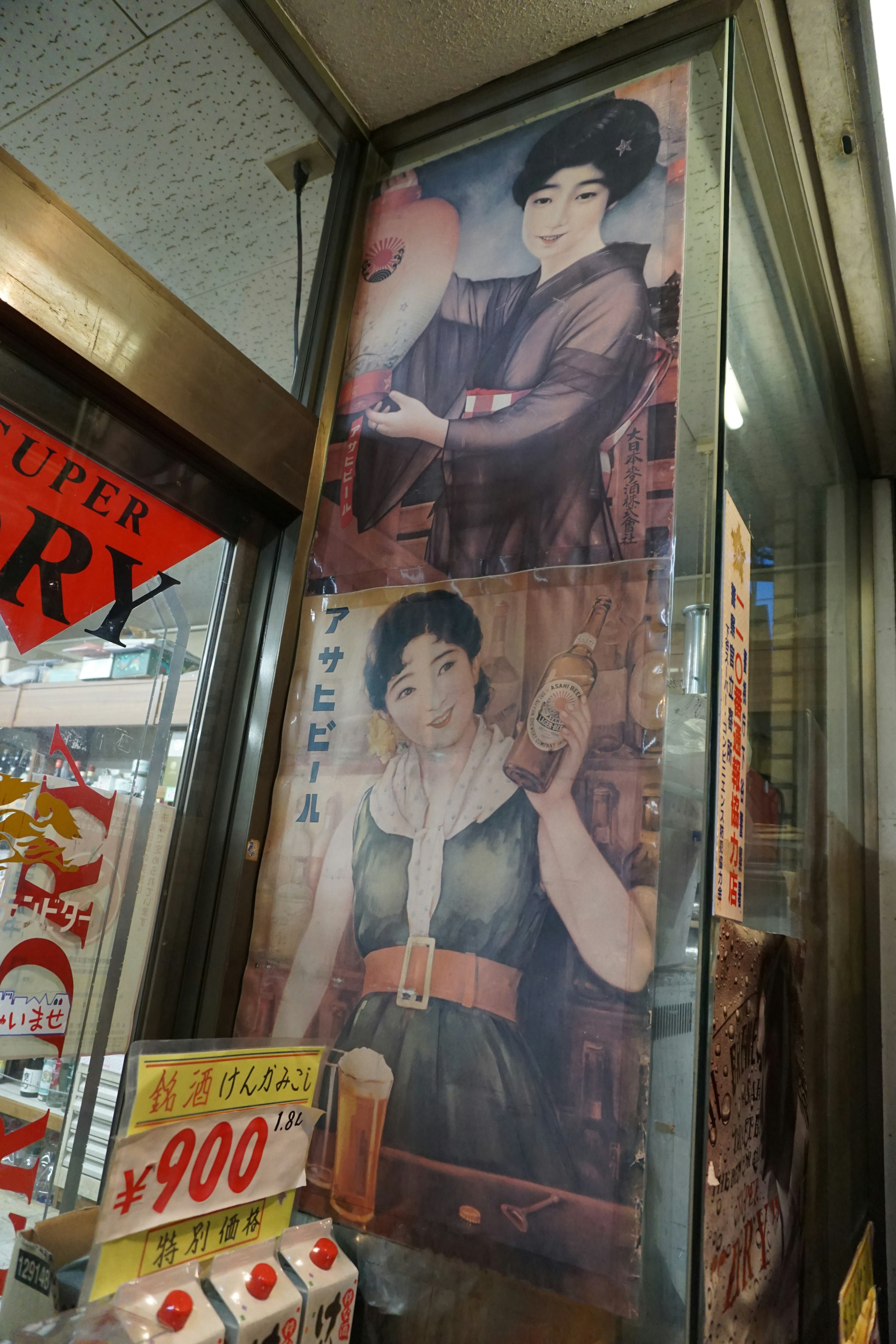 Dos carteles de mujeres con vestimenta tradicional japonesa exhibidos en una pared de tienda