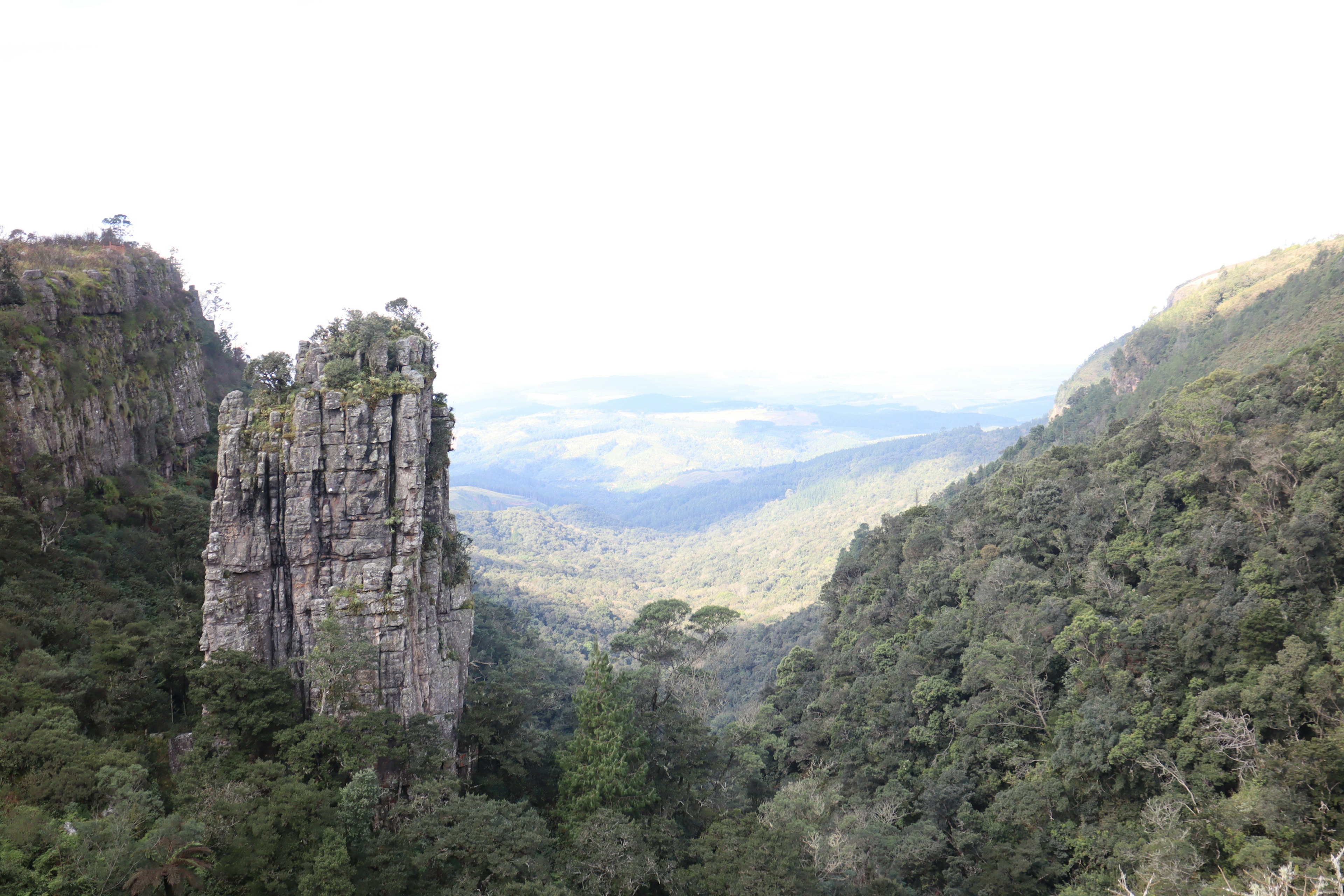 Lembah hijau subur dengan tebing menjulang dan gunung jauh