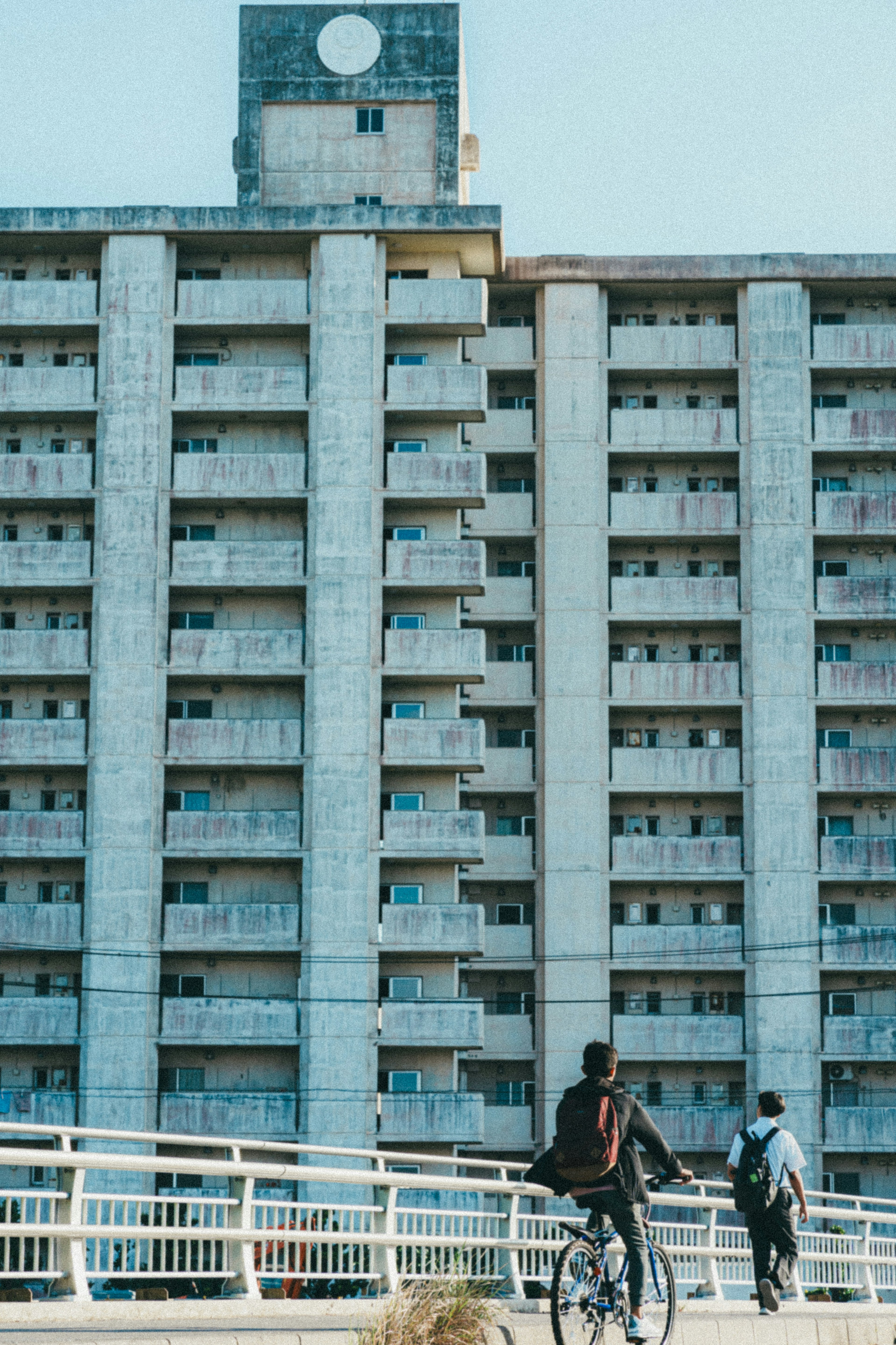 人們在高大的混凝土建築前騎自行車