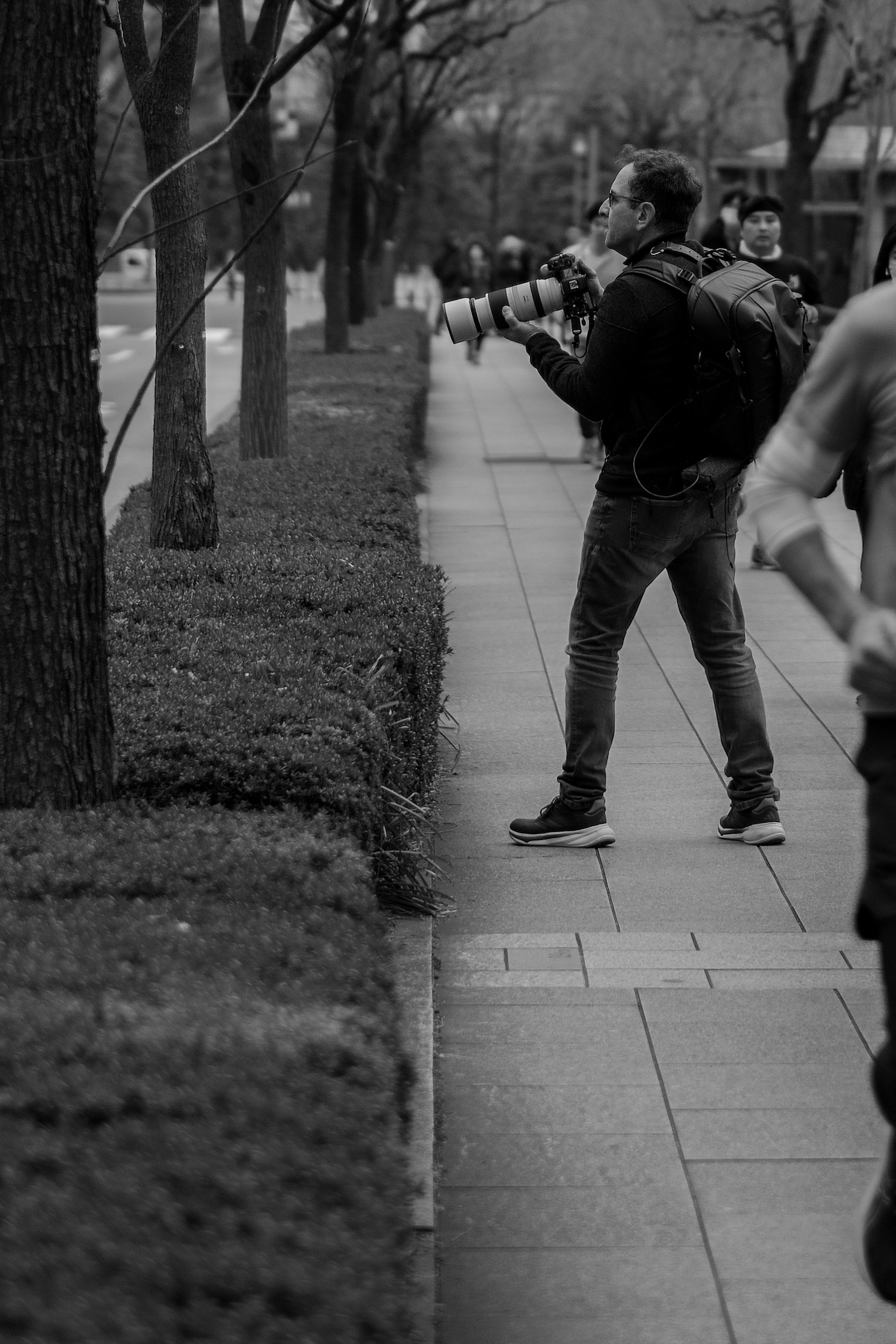 在城市人行道上用相机拍照的男人