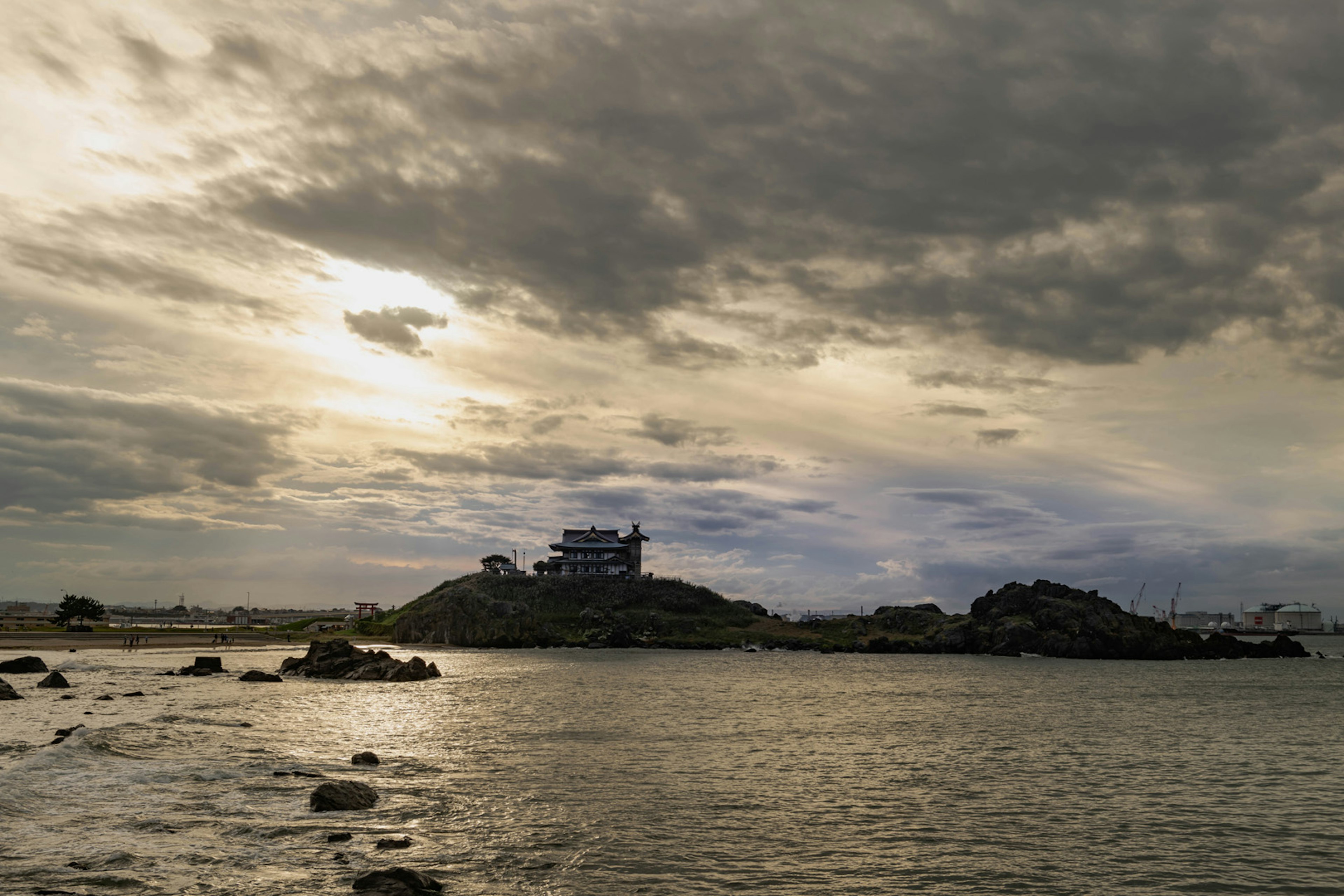 Une petite île entourée d'eau avec un bâtiment au sommet sous un ciel nuageux