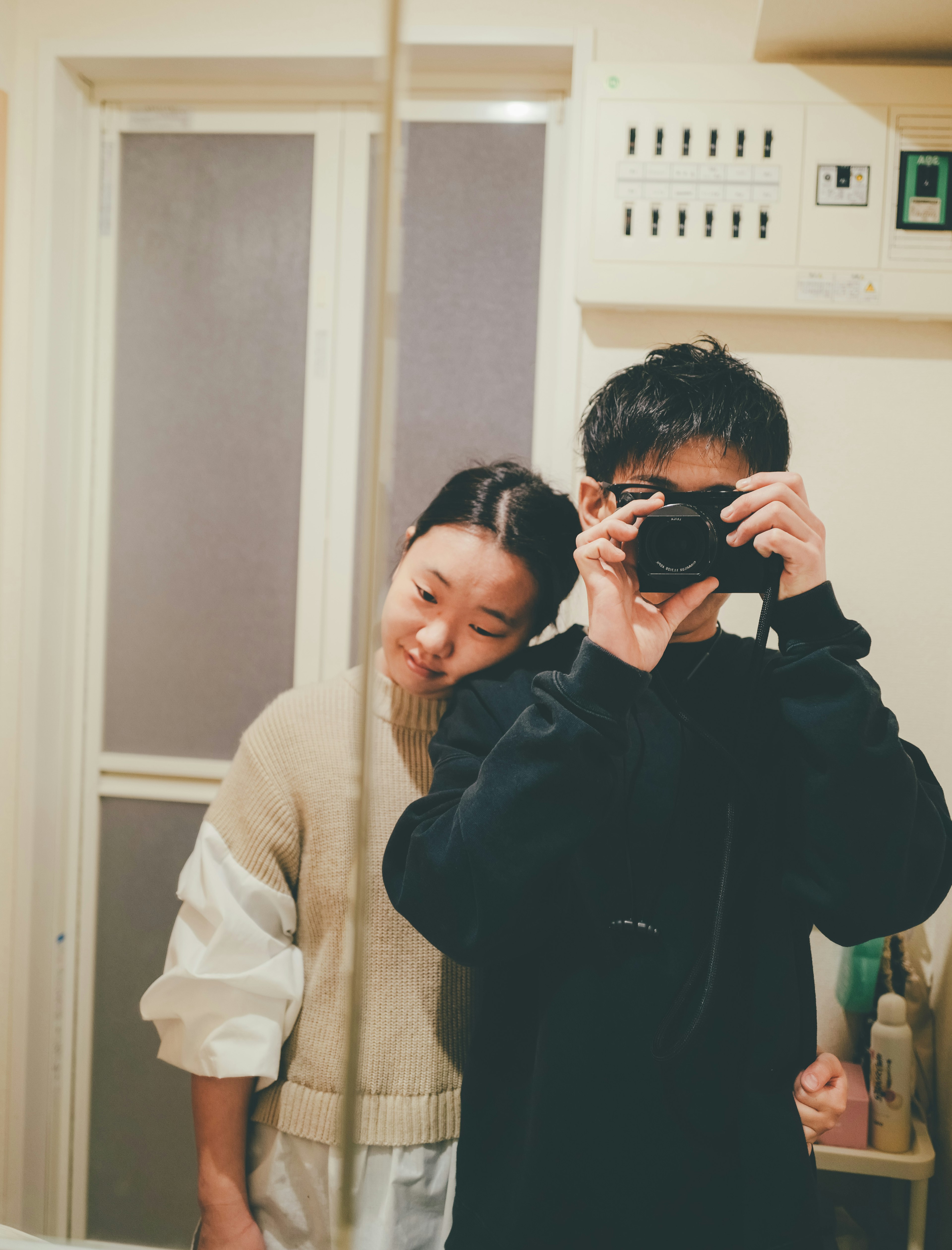 Deux jeunes prenant un selfie devant un miroir L'un tient un appareil photo tandis que l'autre se penche