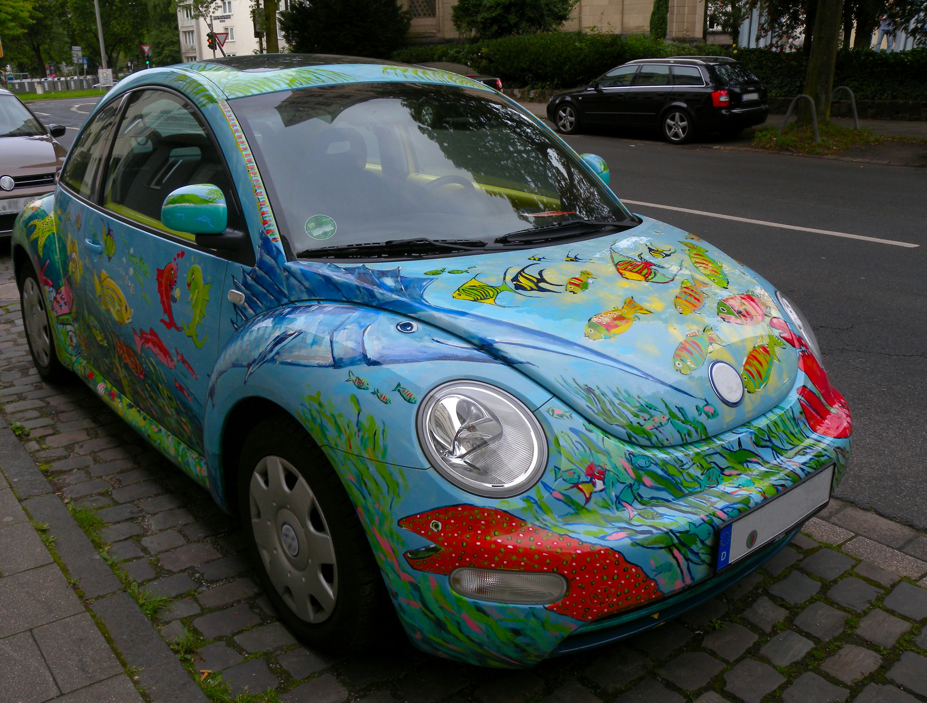 Una macchina Beetle colorata con un tema di pesci parcheggiata per strada