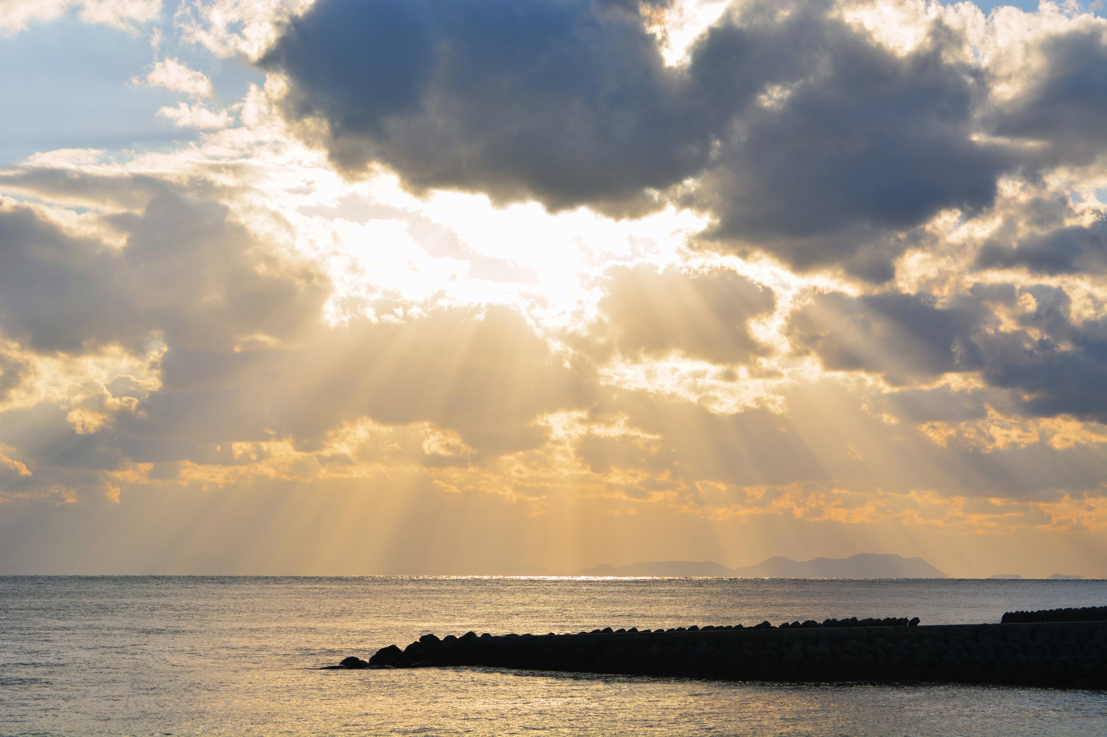 Ruhiges Meer mit Lichtstrahlen, die durch die Wolken scheinen