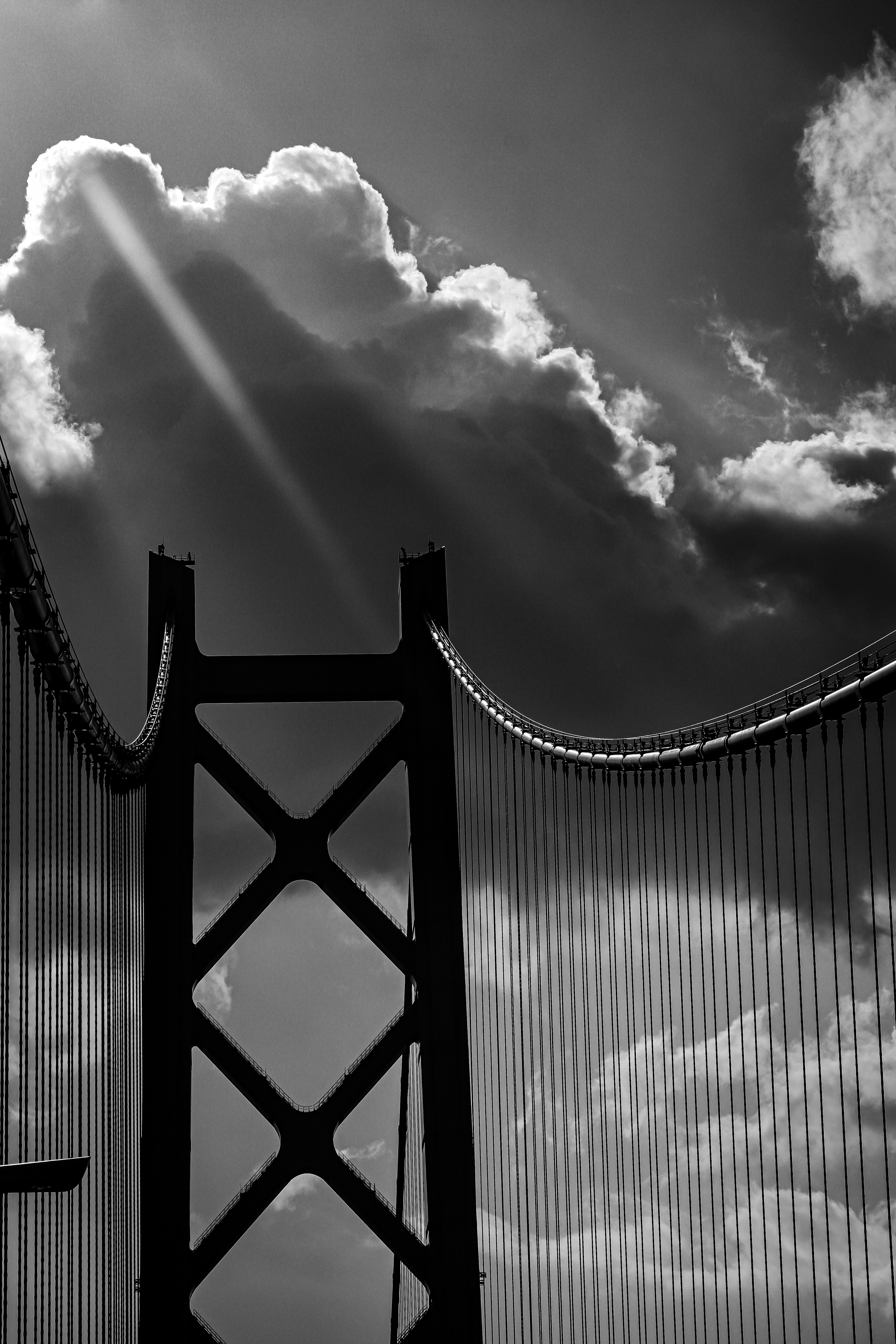 Silhouette di un ponte con nuvole retroilluminate in bianco e nero