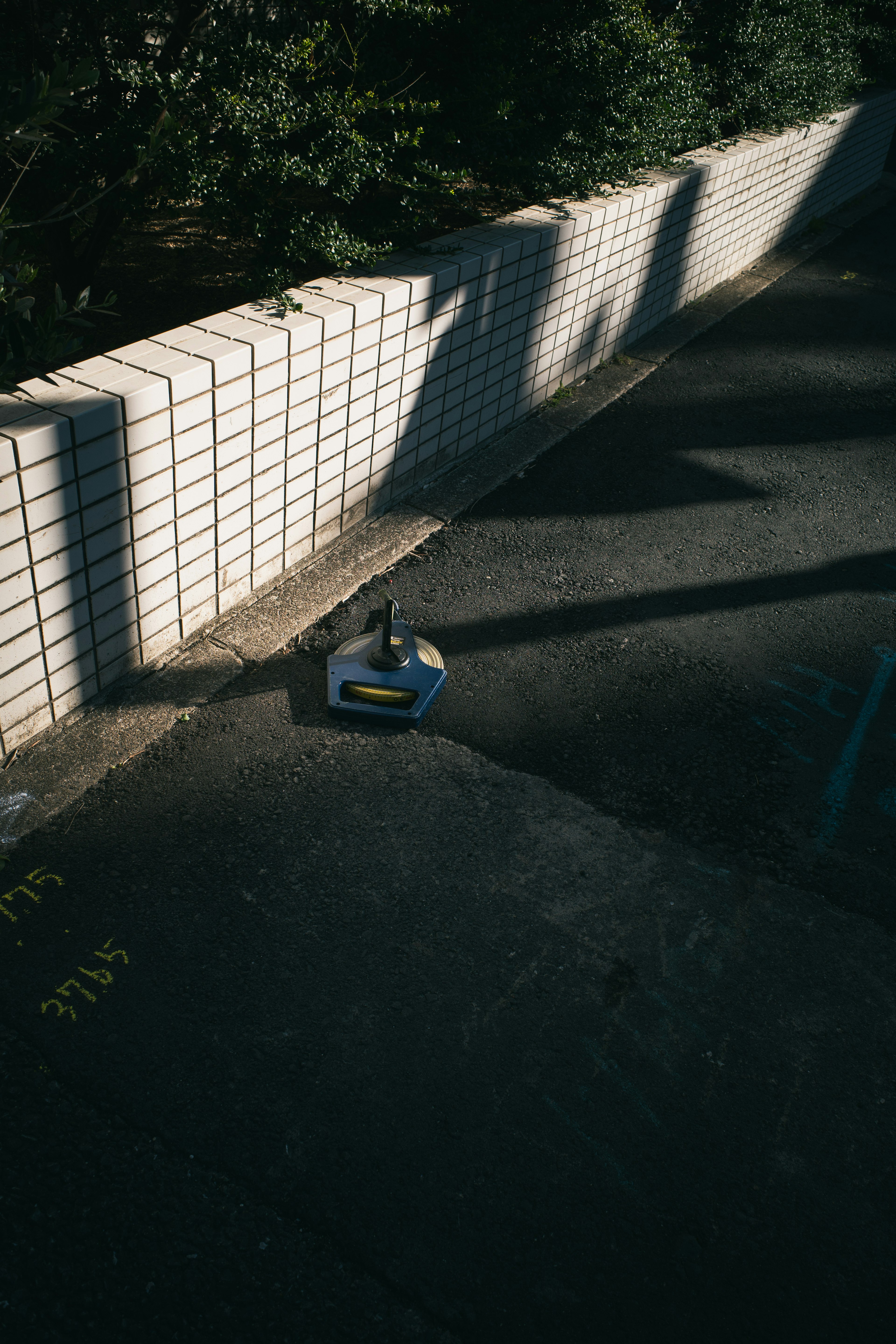 Black bottle on paved ground casting a long shadow