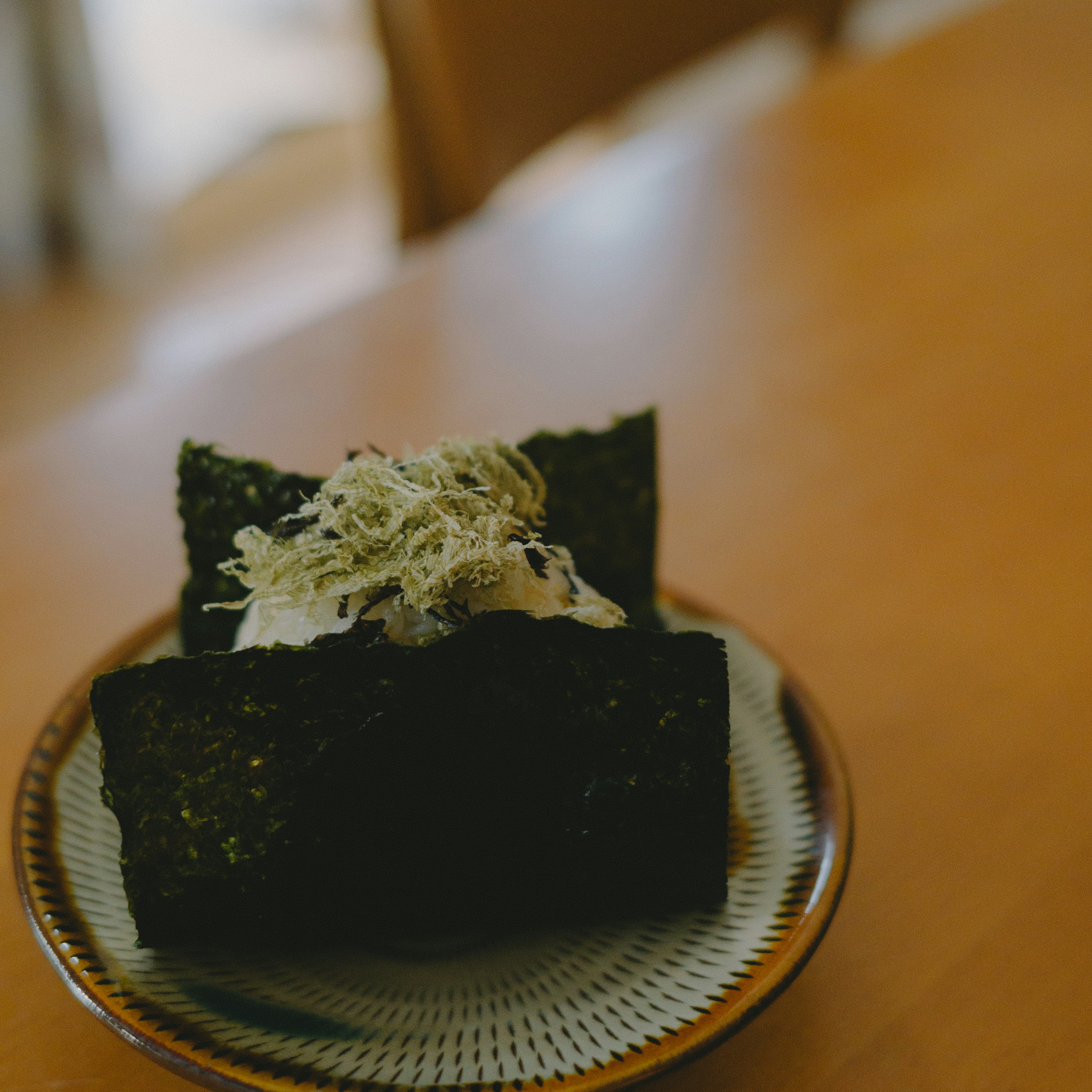 Two pieces of seaweed-wrapped food on a decorative plate