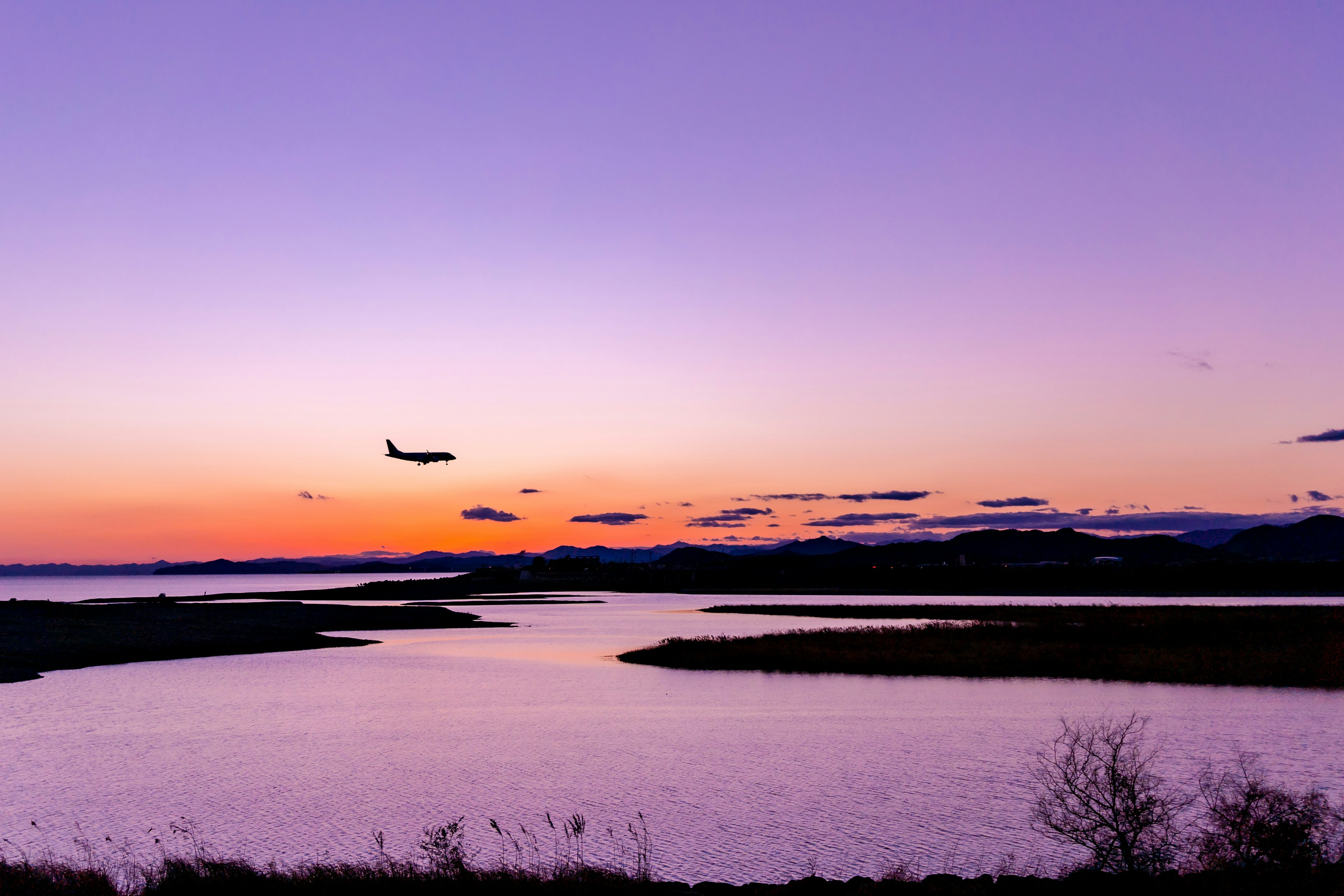 夕焼け空を背景に飛行機が飛ぶ風景