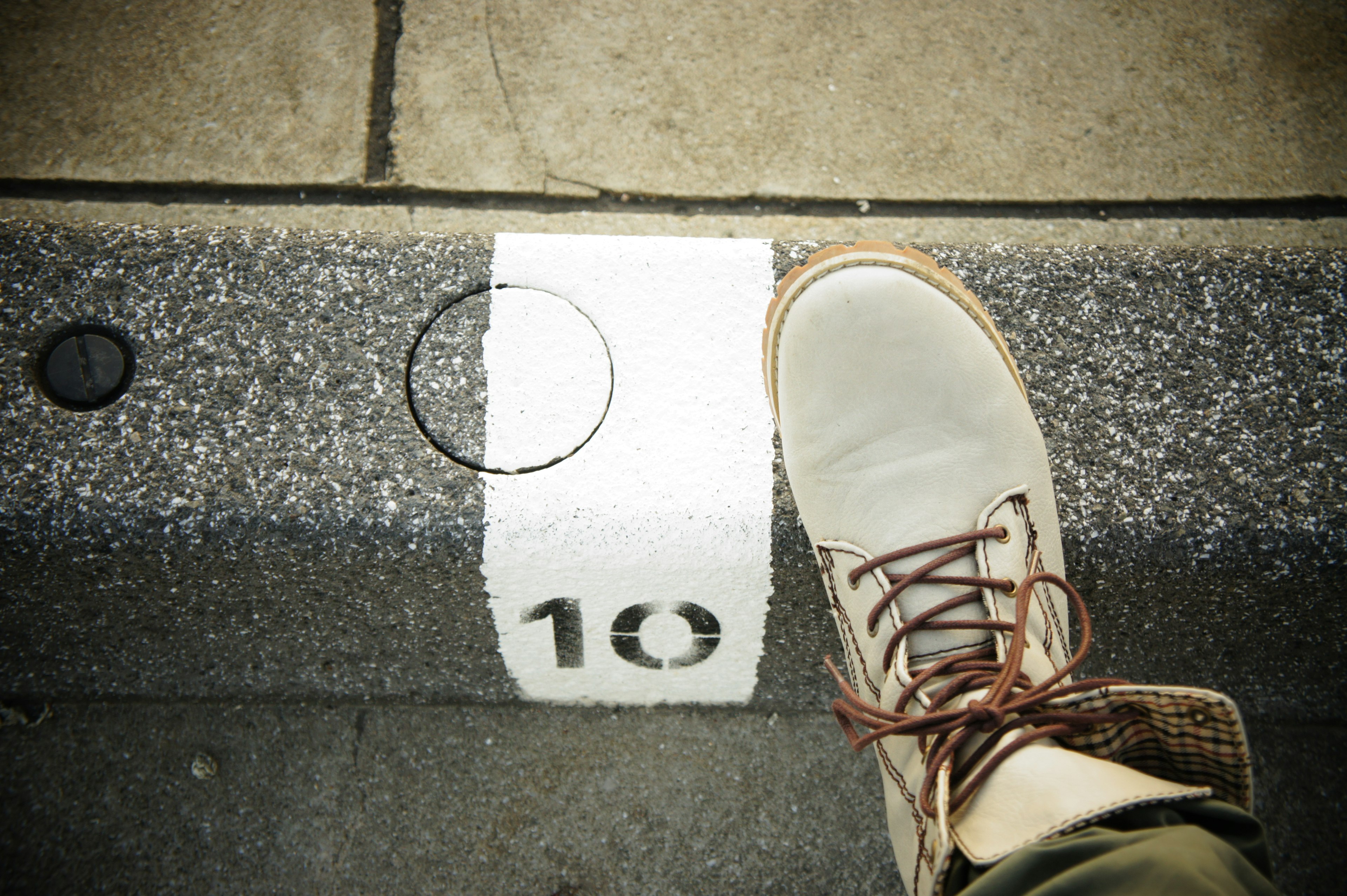 Brown shoe resting on white marker with the number 10