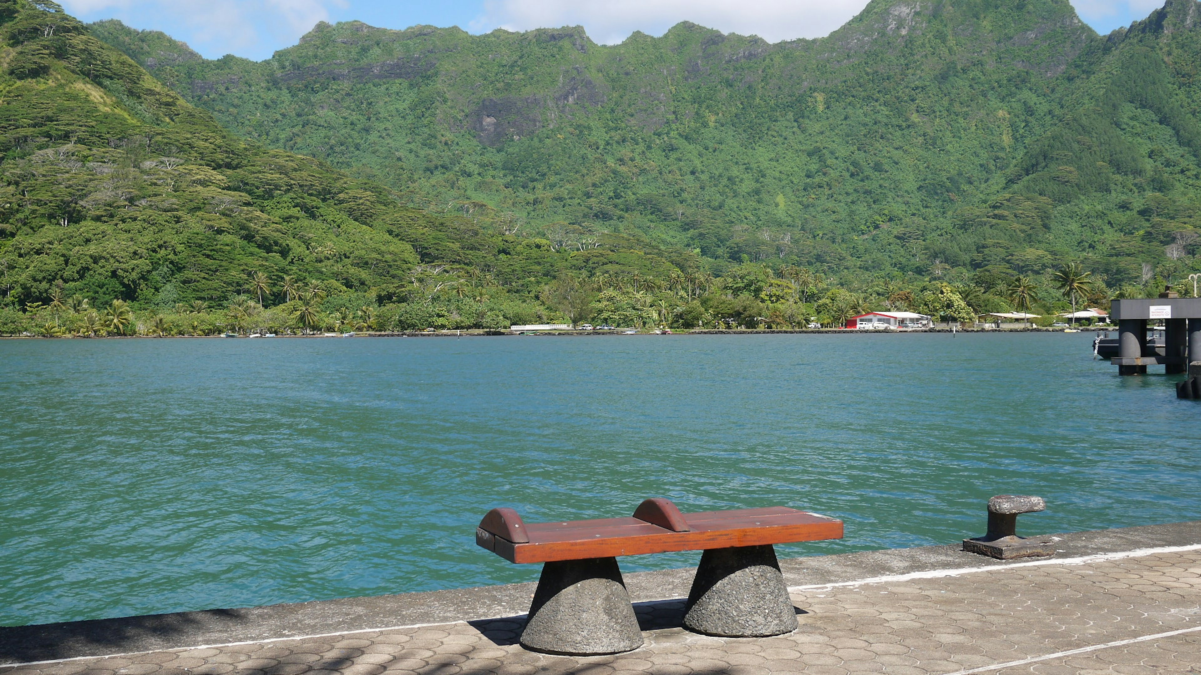 Wooden bench by the turquoise water with lush green mountains