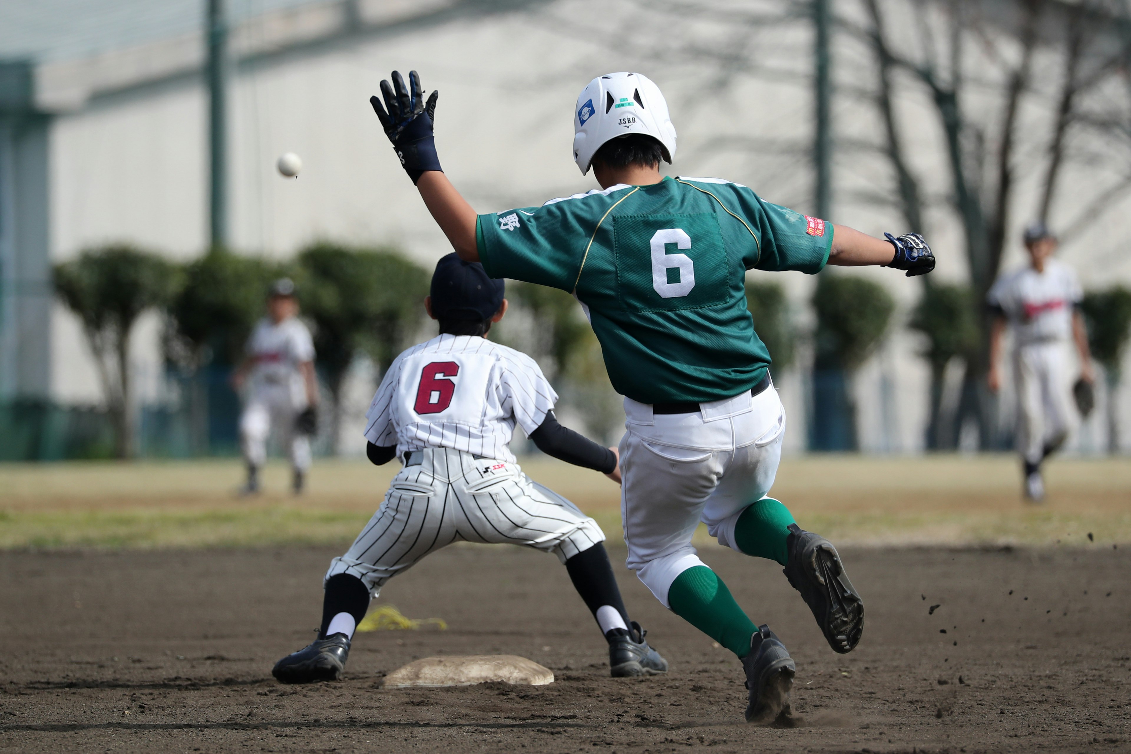 Giocatori di baseball in azione con uno che cerca di raggiungere la seconda base