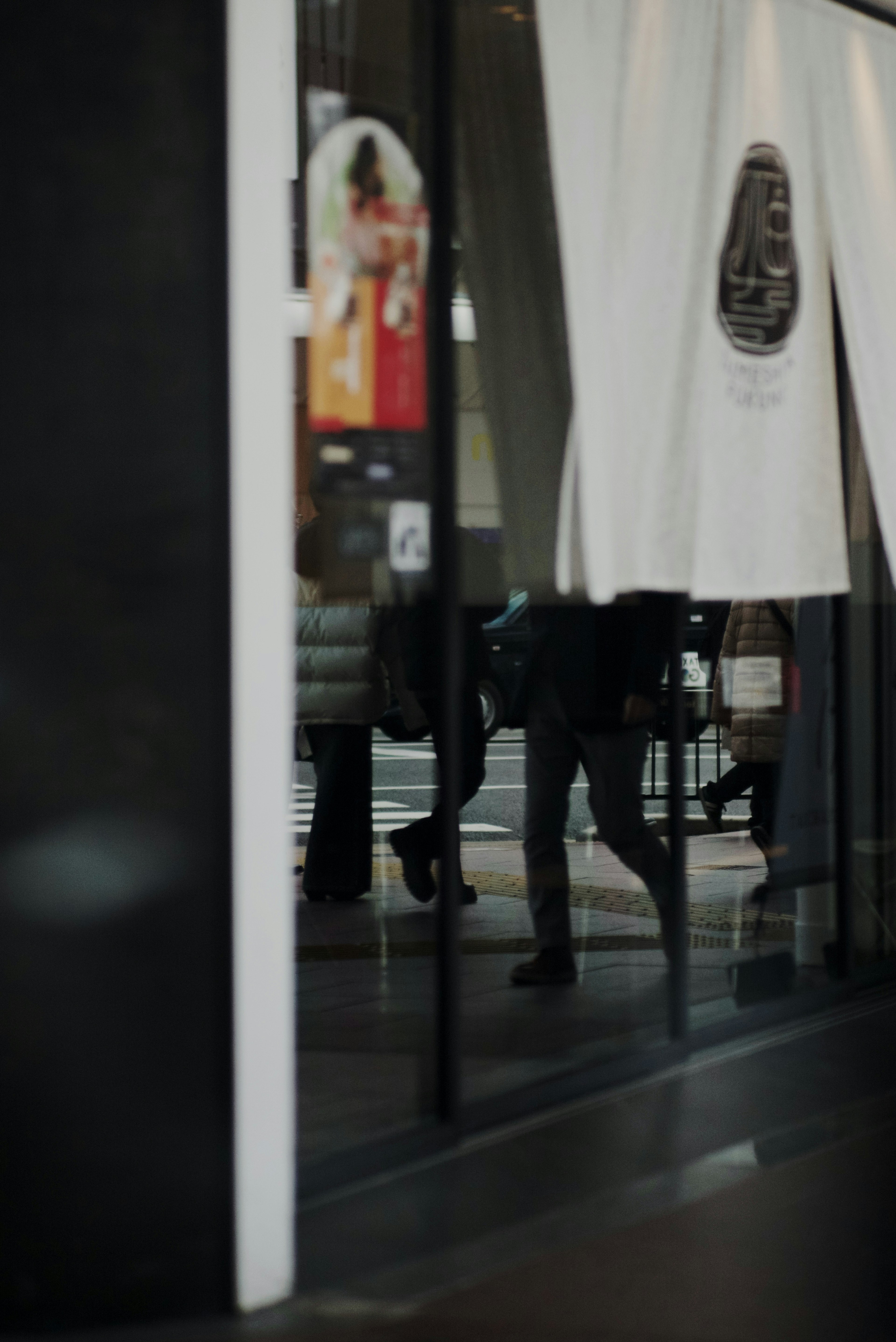 Réflexion de personnes dans une vitre avec des rideaux blancs dans un intérieur de magasin