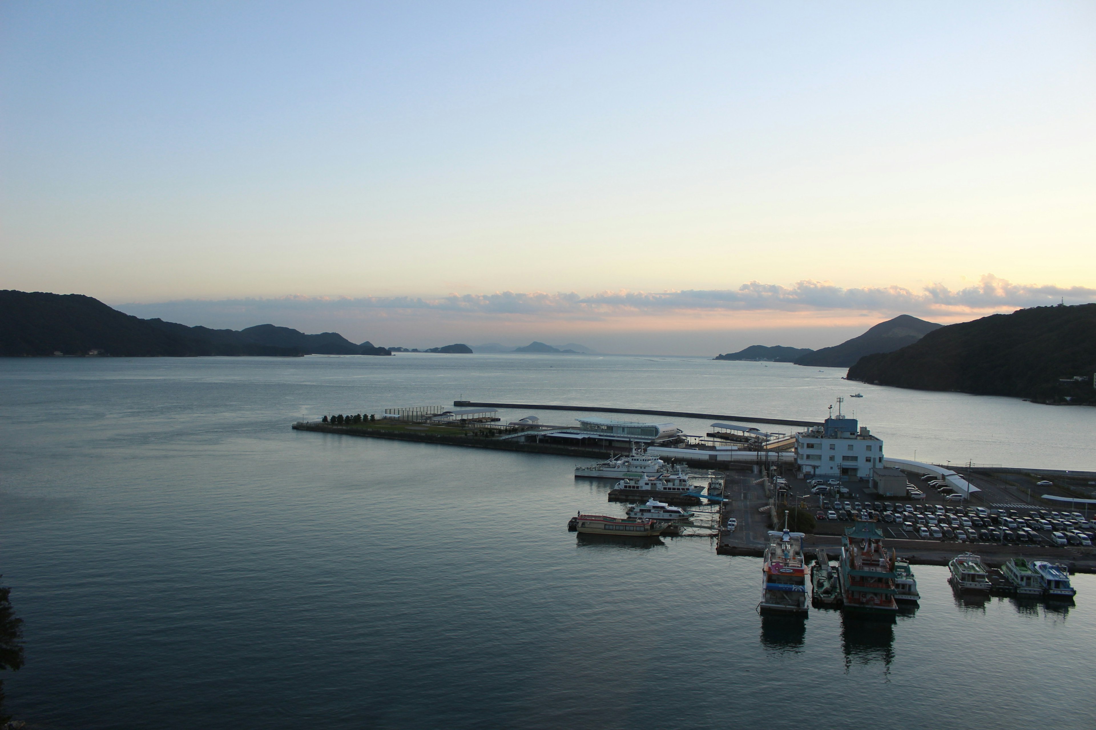 Vue pittoresque d'un port au coucher du soleil avec des eaux calmes et des collines lointaines