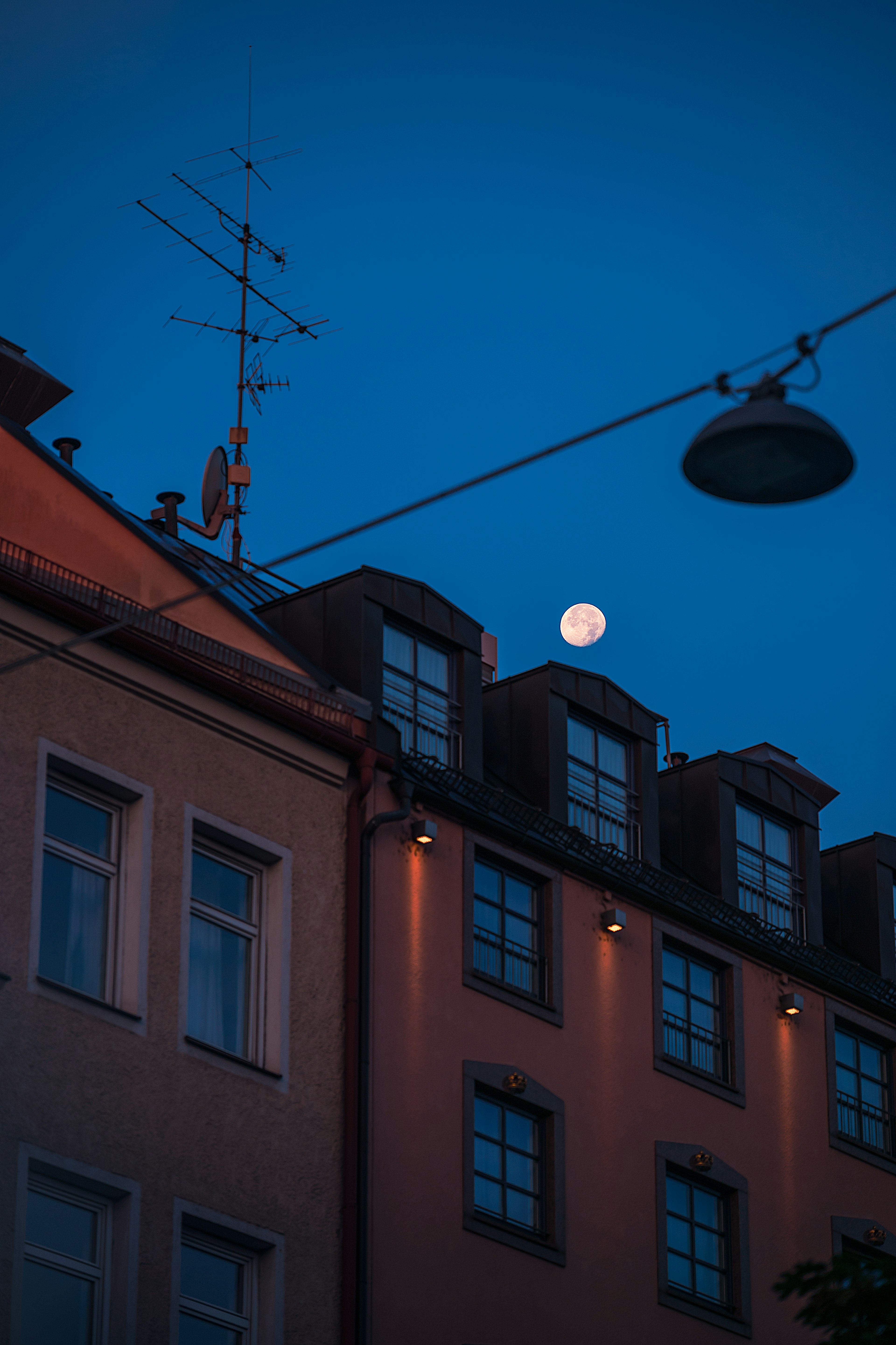 Facade of a building with a full moon in the night sky and streetlight