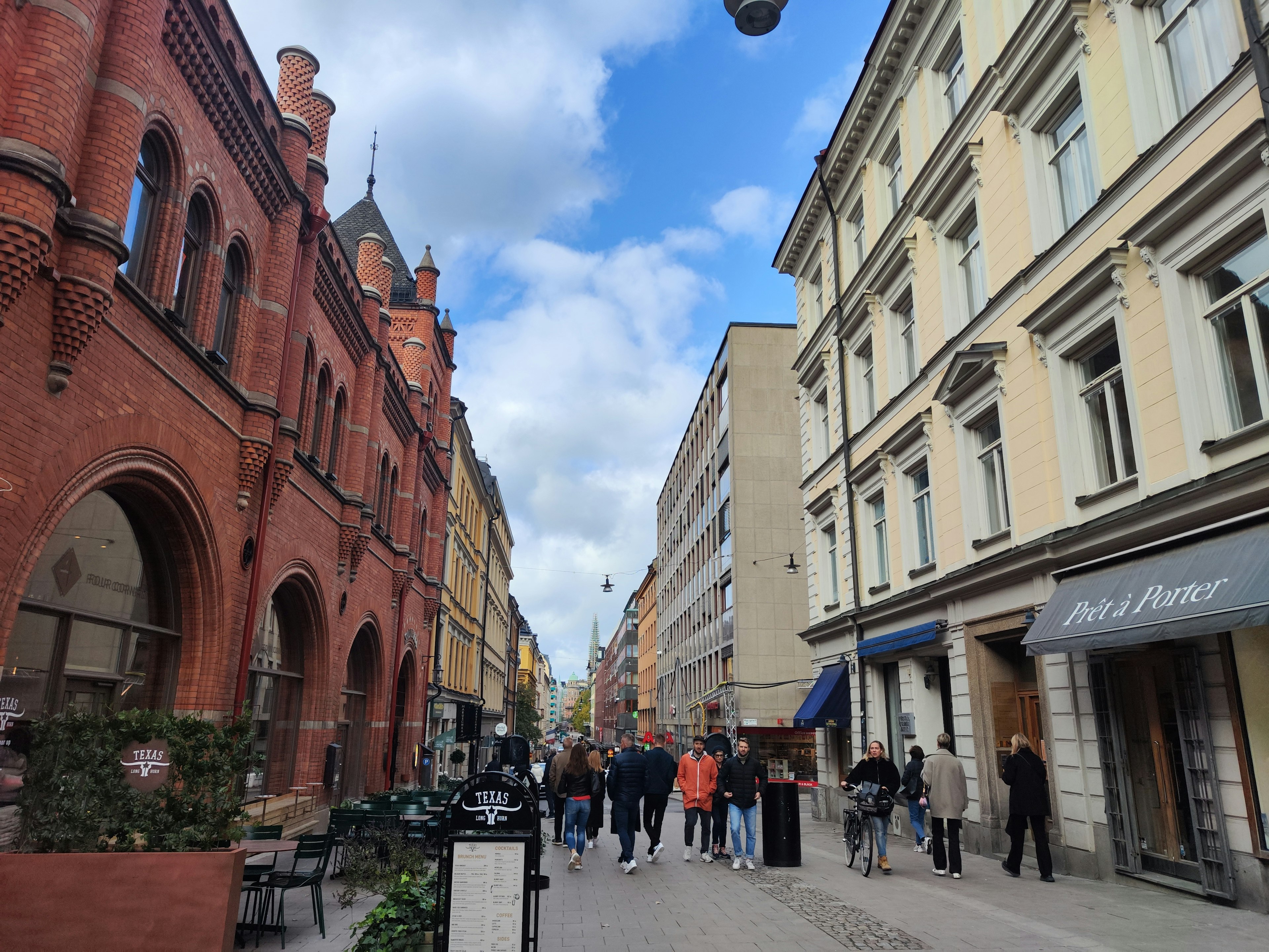 Una escena de calle con edificios de ladrillo rojo y arquitectura moderna con personas caminando